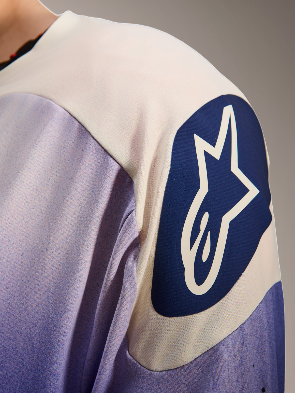 Alpinestars A-Aria Polartec Maker Elite Jersey, Long Sleeve Mountain Bike Jersey, Baja Blue and white, close-up of the shoulder featuring a large blue circular Alpinestars logo with a white star, showing laser perforations and technical fabric texture