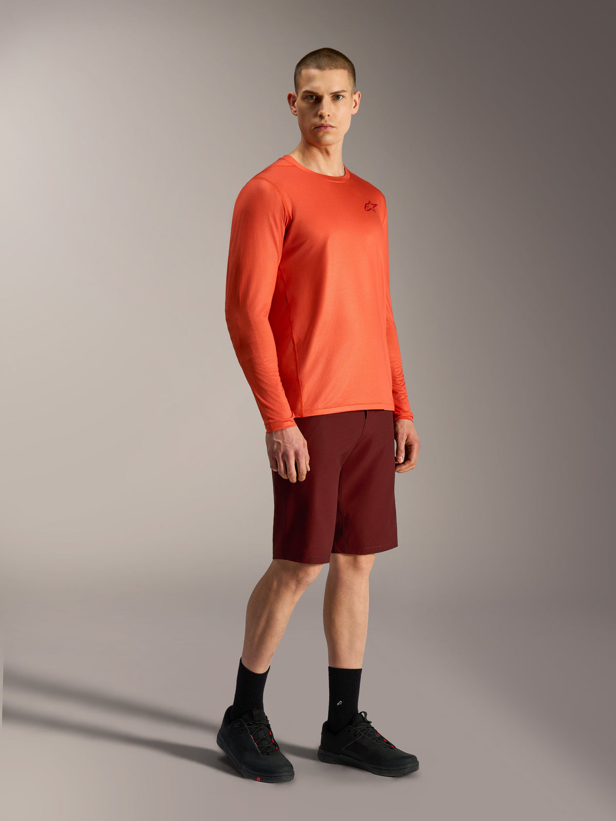 Oranges Alpinestars A-Dura Air LS Jersey und bordeauxrote A-Dura Ride Shorts, funktionale MTB-Ausrüstung.