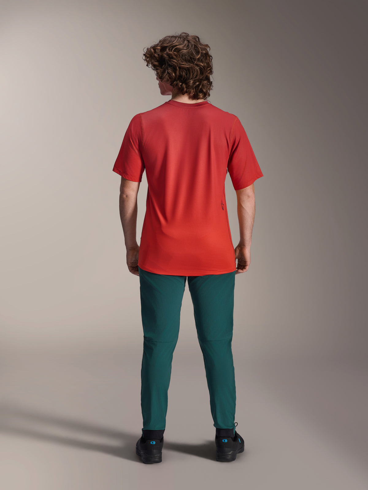 Alpinestars A-Dura Pants in Dark Pine green, mountain bike trousers worn with a red short-sleeve jersey, back view, athletic fit for off-road cycling.