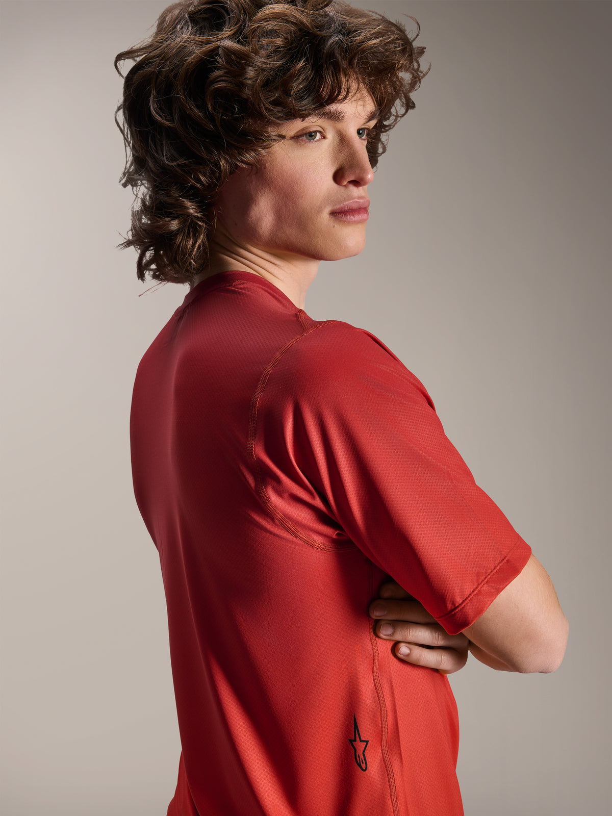 Alpinestars A-Dura Rise Kurzarmtrikot, Spicy Orange, Modellansicht von der Seite und von hinten, zeigt ein kleines schwarzes Astars-Logo am unteren Saum, leichtes, strukturiertes Jacquard-Gewebe für MTB-Performance