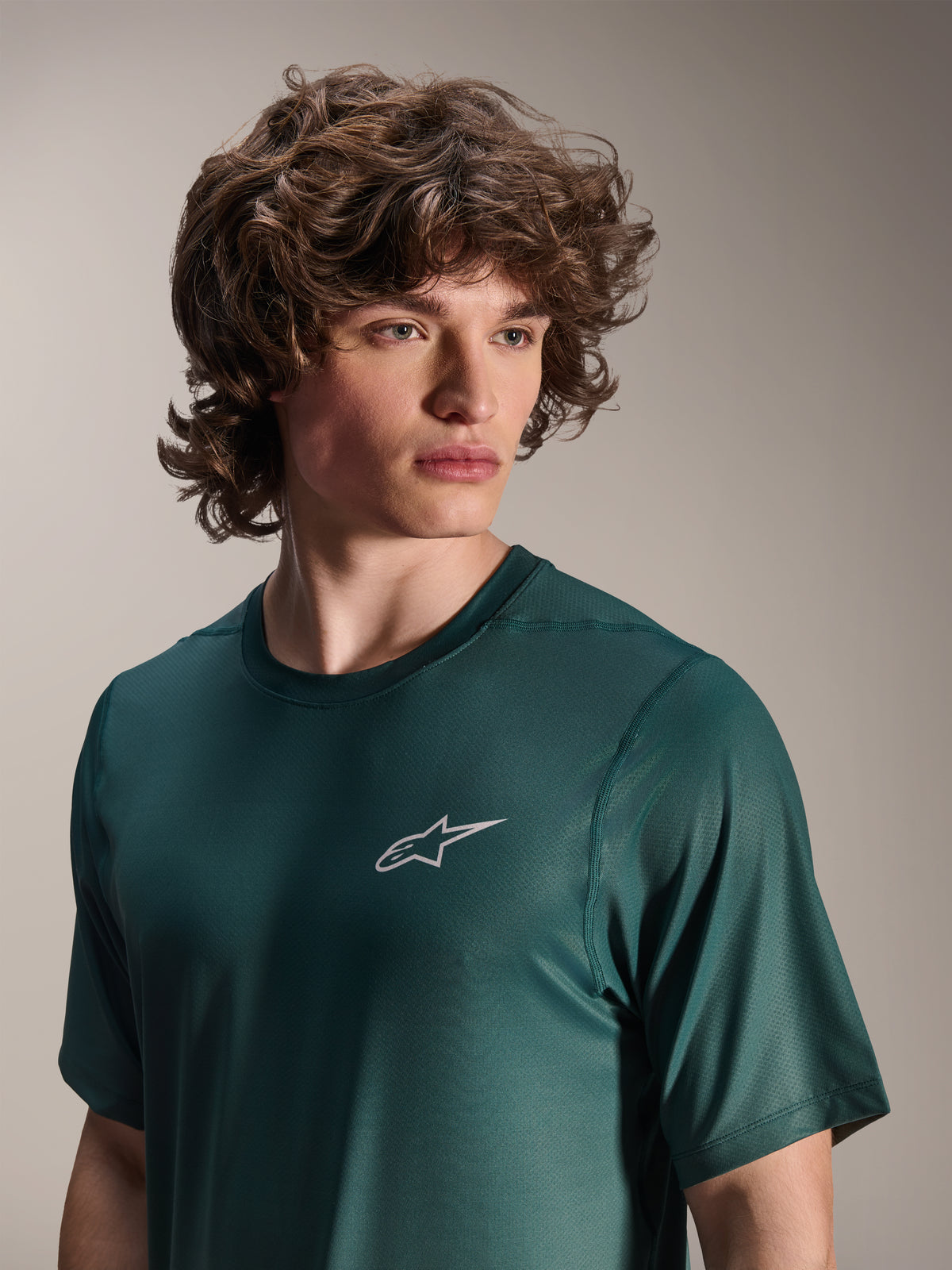 Alpinestars A-Dura Rise Kurzarmtrikot, Silver Pine Grün, von einem Modell getragen, kleines weißes Astars-Logo auf der Brust, Jacquard-Performance-Gewebe, lässige Mountainbike-Bekleidung