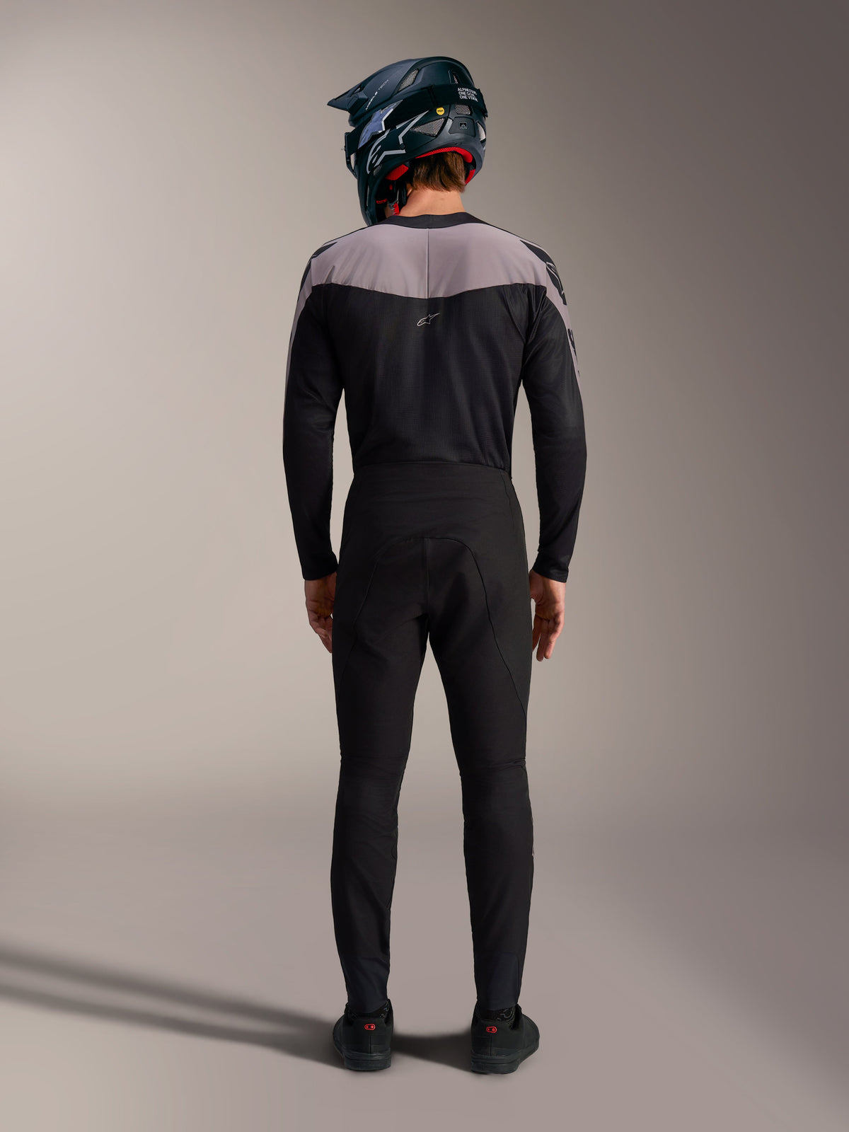 Alpinestars A-Supra Elite MTB-Kit in Schwarz, mit Performance-Hose und Jersey sowie Fullface-Helm, Rückansicht.