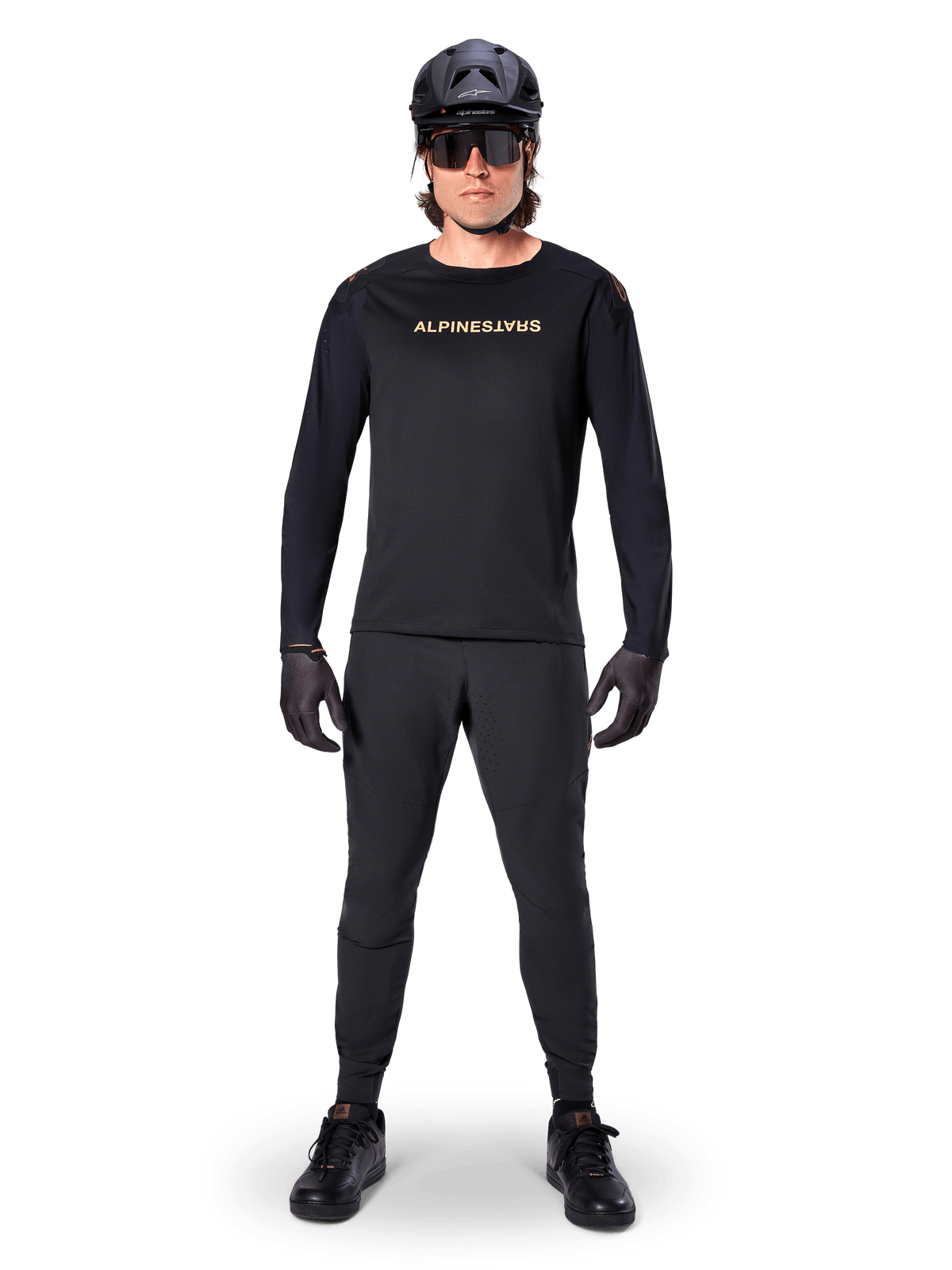 Alpinestars A-Aria Polartec Switch Langarmtrikot, Schwarz, getragen von einem Fahrer mit passender schwarzer technischer Hose, schwarzem Helm, Sonnenbrille und schwarzen Handschuhen, Performance-MTB-Ausrüstung für Offroad-Trails