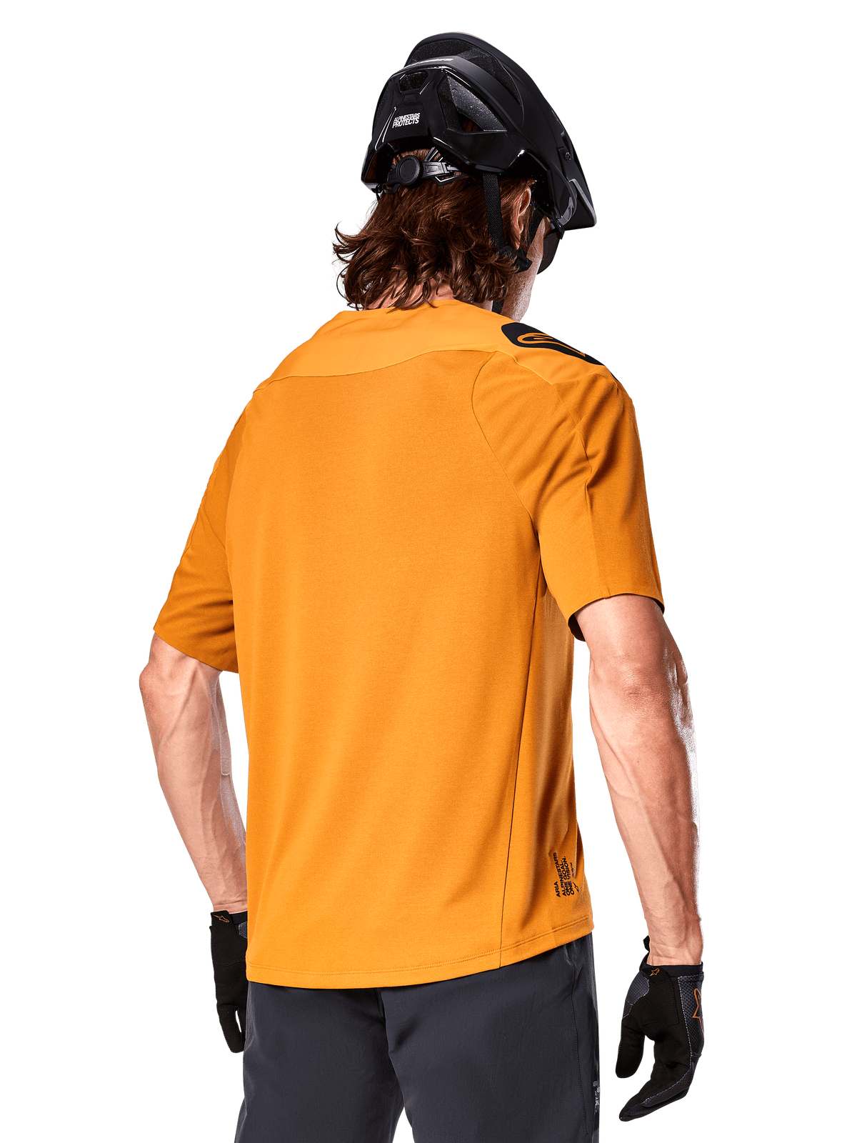 Alpinestars A-Aria Polartec Switch Trikot, Kurzarm-MTB-Trikot, Dunkelgold, Rückansicht mit Performance-Passform, getragen mit schwarzem Helm und grauen Shorts, strapazierfähige und atmungsaktive Trail-Bekleidung
