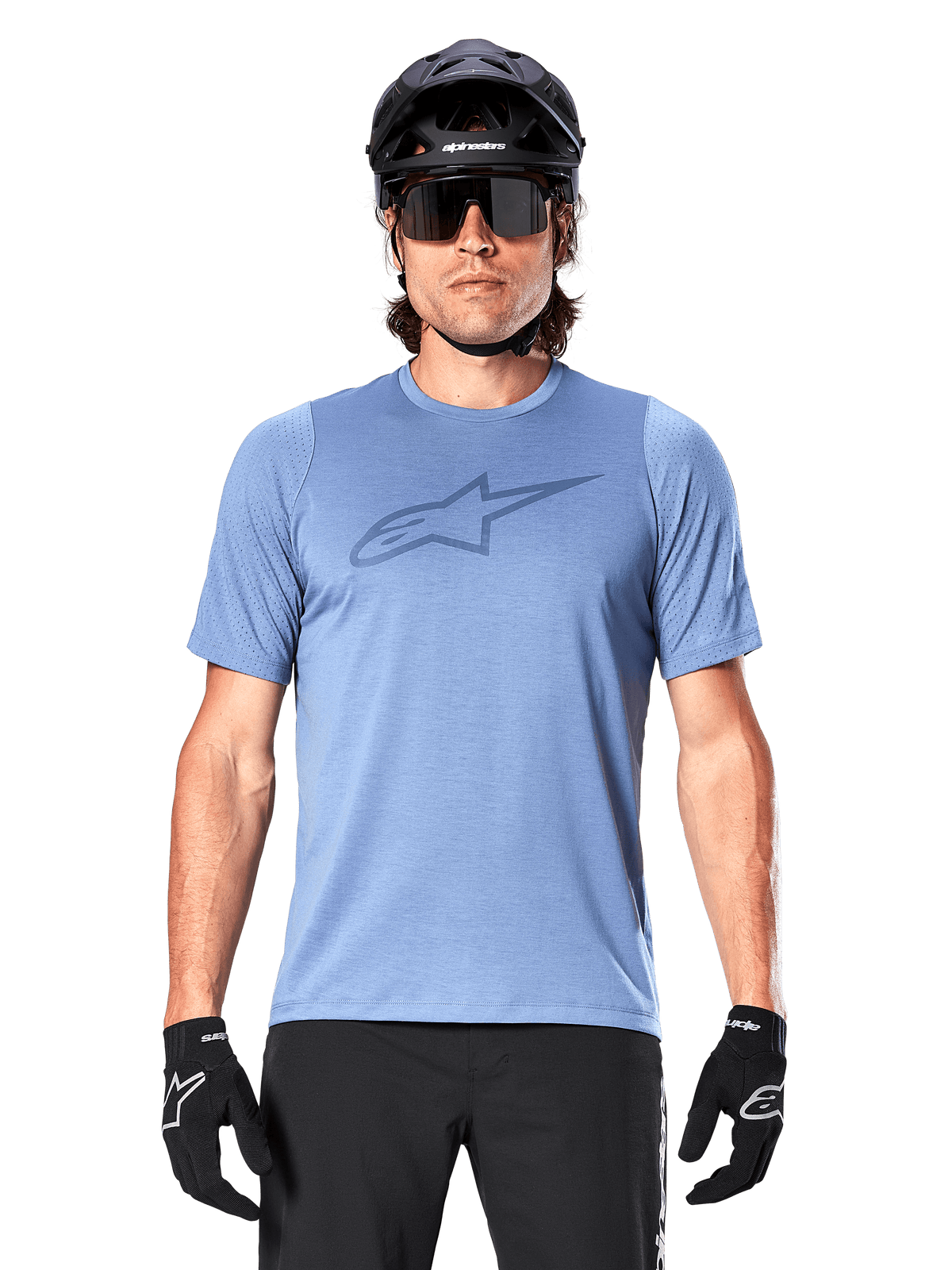 Männlicher Mountainbiker im Alpinestars A-Dura Dri Astar Kurzarmtrikot in Infinity Blue, mit dezentem Brustlogo und Mesh-Einsätzen, kombiniert mit einem schwarzen Helm, einer Sonnenbrille und schwarzen Handschuhen für ein technisches Radsport-Outfit
