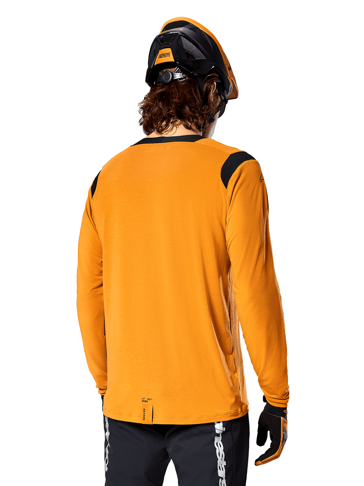 Alpinestars A-Dura Dri Wool Langarmtrikot in Dark Gold, Rückansicht eines Fahrers mit Mountainbike-Helm und Handschuhen, verfügt über schwarze Mesh-Einsätze an den Schultern und ein verlängertes Rückenteil, technische Radsportbekleidung für Trailfahrten
