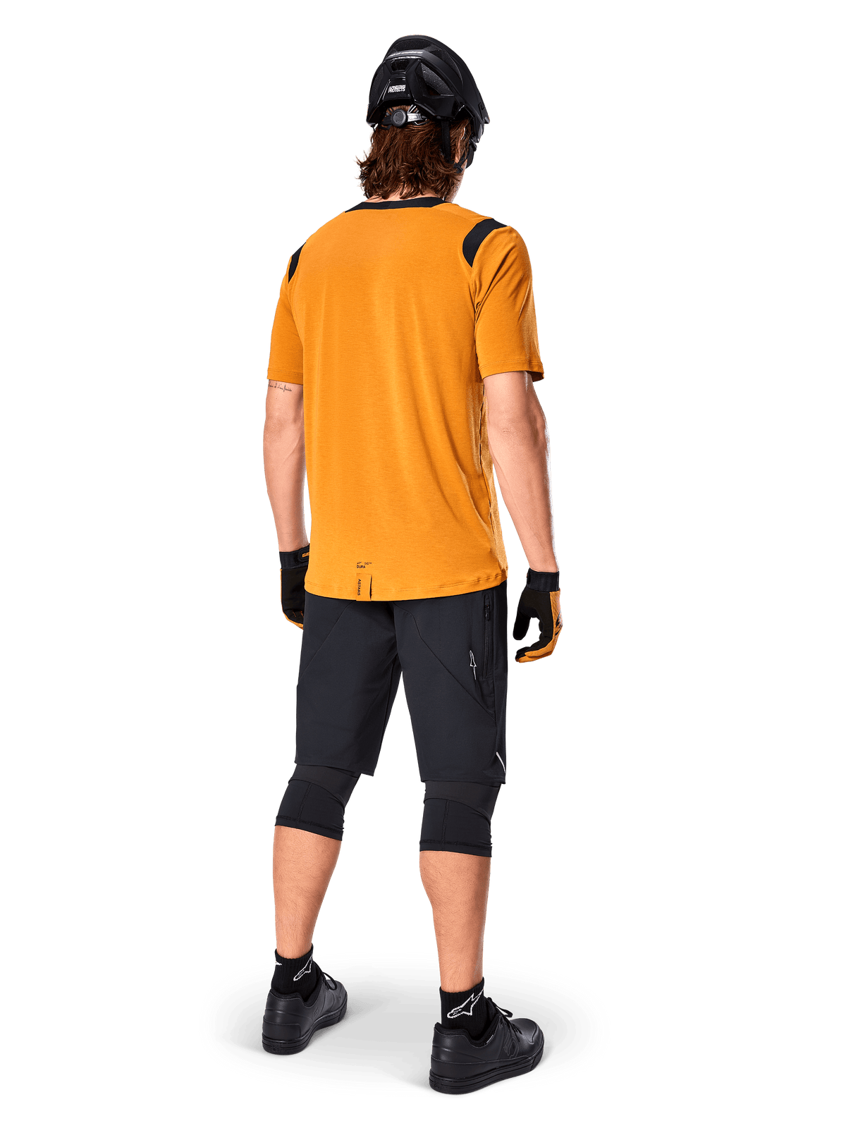 Alpinestars A-Dura Dri Wool Short Sleeve Jersey, Cycling Jersey, Dark Gold, back view of mountain biker wearing mustard-yellow jersey with black mesh shoulder accents, paired with black shorts, knee guards, black helmet, and gloves, technical off-road cycling gear