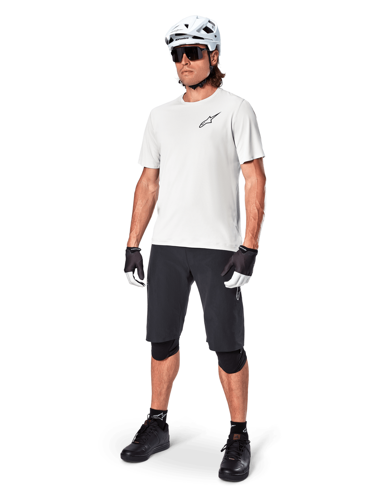 MTB-Fahrer trägt Alpinestars A-Aria Astar Kurzarmtrikot in White Dove, kombiniert mit schwarzen Mountainbike-Shorts, weißem Helm und schwarzen Knieschonern, mit kleinem schwarzen Logo auf der Brust, koordinierte Fahrradausrüstung für Trail-Performance