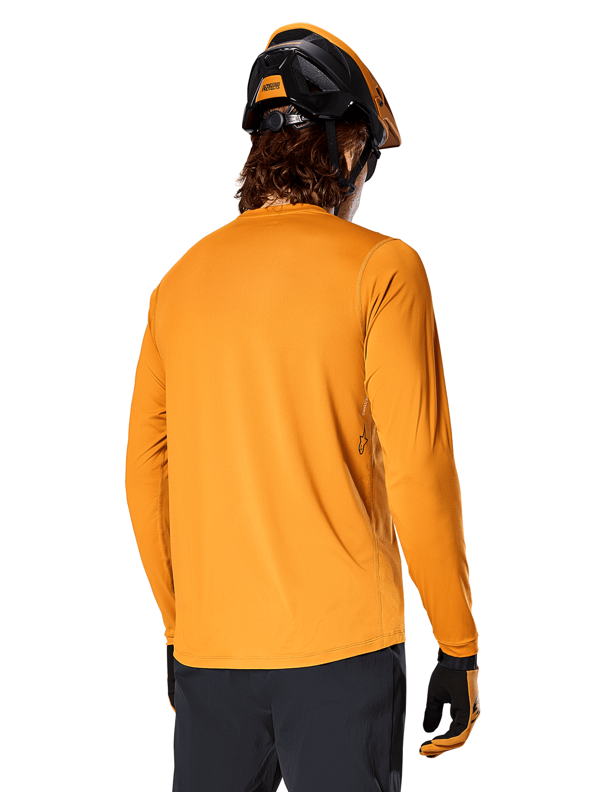 Alpinestars A-Dura Rocker Langarm-Trikot, Dunkelgold, Rückansicht eines Fahrers mit schwarz-orangem MTB-Helm, dunkler Hose und passenden Handschuhen, lässige Performance-Mountainbike-Bekleidung