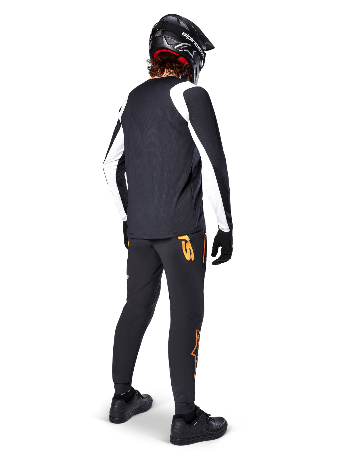Alpinestars A-Supra Oscar Langarmtrikot, Schwarz mit weißen Einsätzen an den Ärmeln, Rückansicht eines MTB-Fahrers mit schwarzem Fullface-Helm und schwarzer Hose mit orangen Logos, Radsportbekleidung für Offroad-Gravity-Fahrten