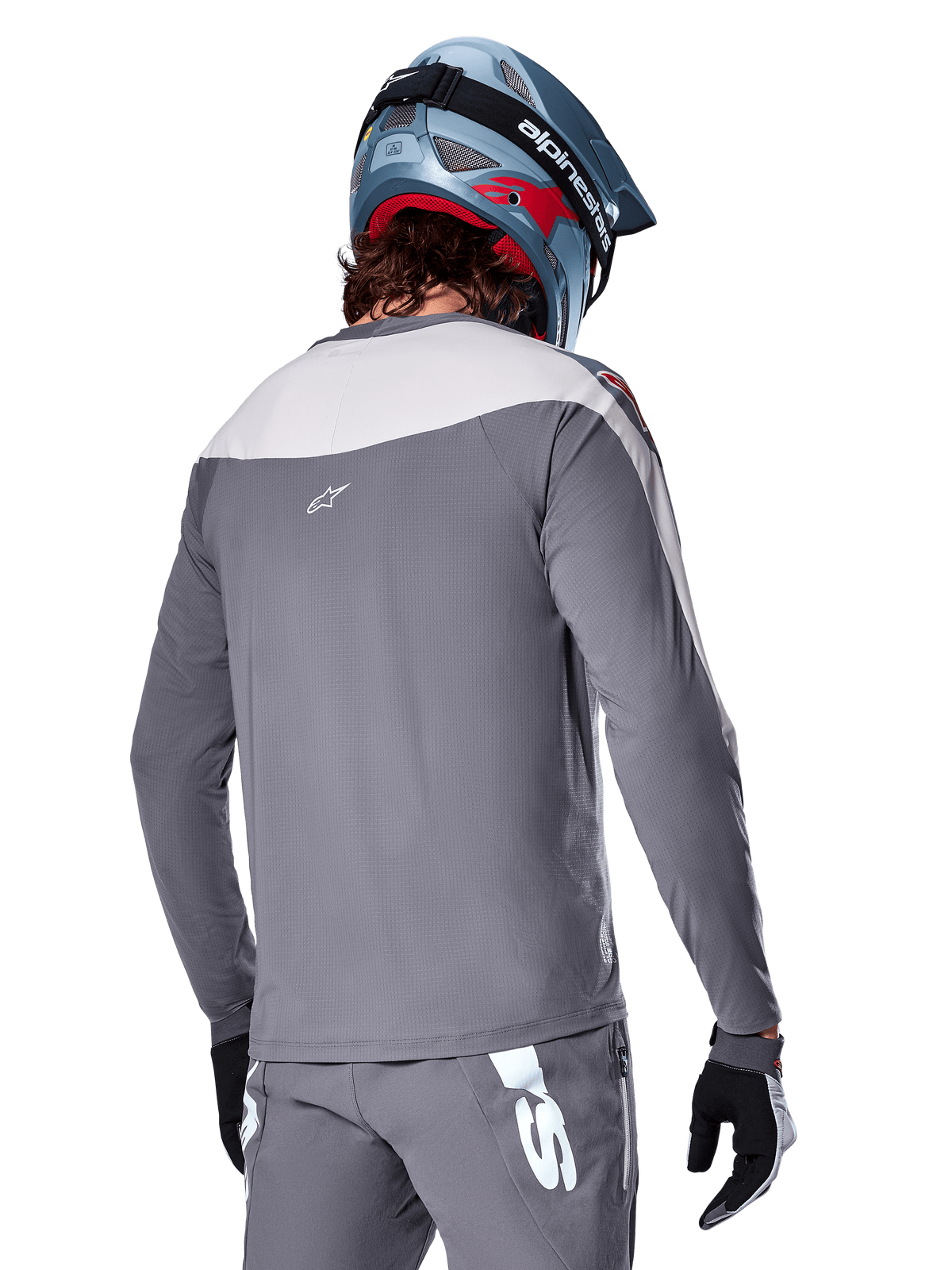 Alpinestars A-Supra Race Trikot, Langarm-MTB-Trikot in Dunkelgrau und Hellgrau, Rückansicht mit Performance-Passform und Astar-Logo, getragen mit passender grauer Hose und einem blauen Mountainbike-Helm, entwickelt für Offroad-Mountainbiking.