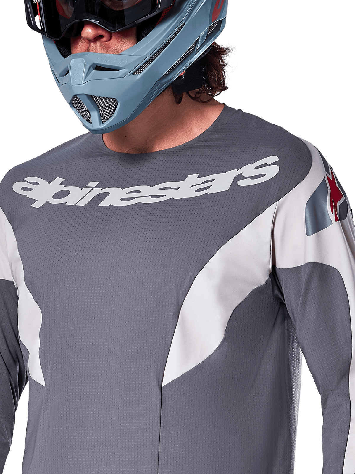 Alpinestars A-Supra Race Trikot – Langarm, MTB-Trikot, Dunkelgrau mit weißen Renngrafiken und weißem Alpinestars-Logo, getragen mit einem hellblauen Fullface-Helm und einer Goggle, mikroperforiertes Gewebe für Offroad-Performance