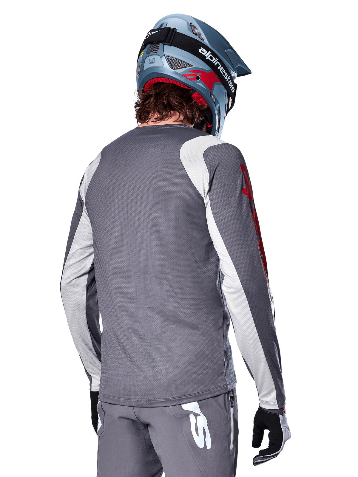 Alpinestars A-Supra Astar Langarmtrikot, Dunkelgrau mit hellgrauen Schulter- und Arm-Einsätzen, Rückansicht eines Fahrers mit blauem Fullface-Mountainbike-Helm und grauer Hose, MTB-Bekleidung mit Performance-Passform