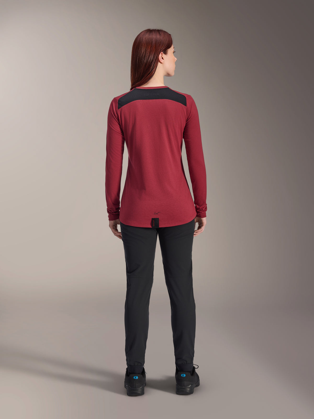 Alpinestars Stella A-Dura Dri Astar Langarmtrikot für Damen, Burgunderrot mit schwarzen Mesh-Schultereinsätzen, technische MTB-Bekleidung in der Rückansicht mit schwarzer Hose, verlängerter Rückensaum für optimale Abdeckung beim Radfahren