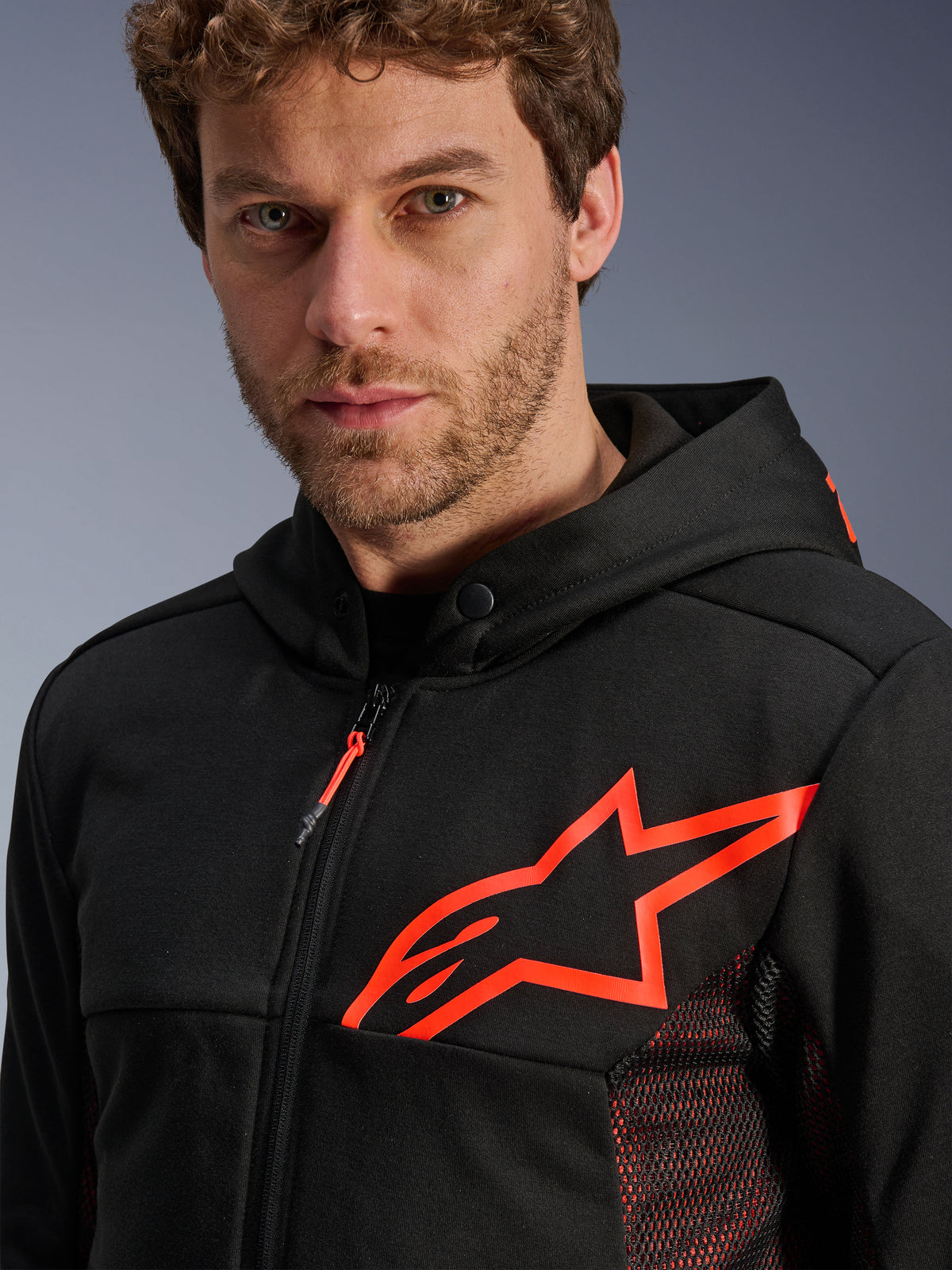 Alpinestars Chrome Air Sport Hoodie, Schwarz und Leuchtrot, Nahaufnahme mit großem leuchtend rotem Stern-Logo auf der Brust, rote Mesh-Seitenpaneele zur Belüftung, Frontreißverschluss und Kragen mit Druckknopf, lässige urbane Motorradbekleidung