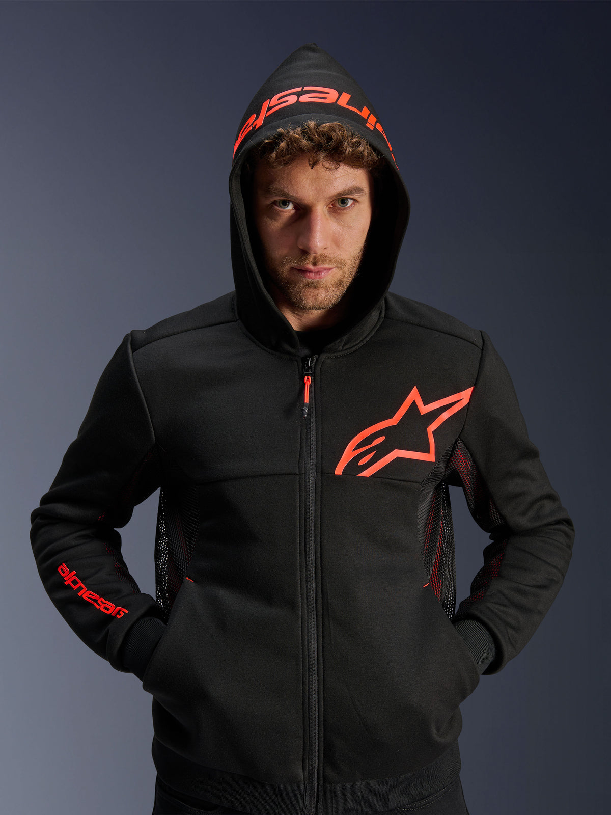 Alpinestars Chrome Air Sport Hoodie, Schwarz und Red Fluo, urbaner Motorrad-Hoodie mit Mesh-Belüftungseinsätzen, rotem Astar-Logo auf der Brust und Kapuze mit Markenschriftzug, lässige Fahrausrüstung für das urbane Umfeld.