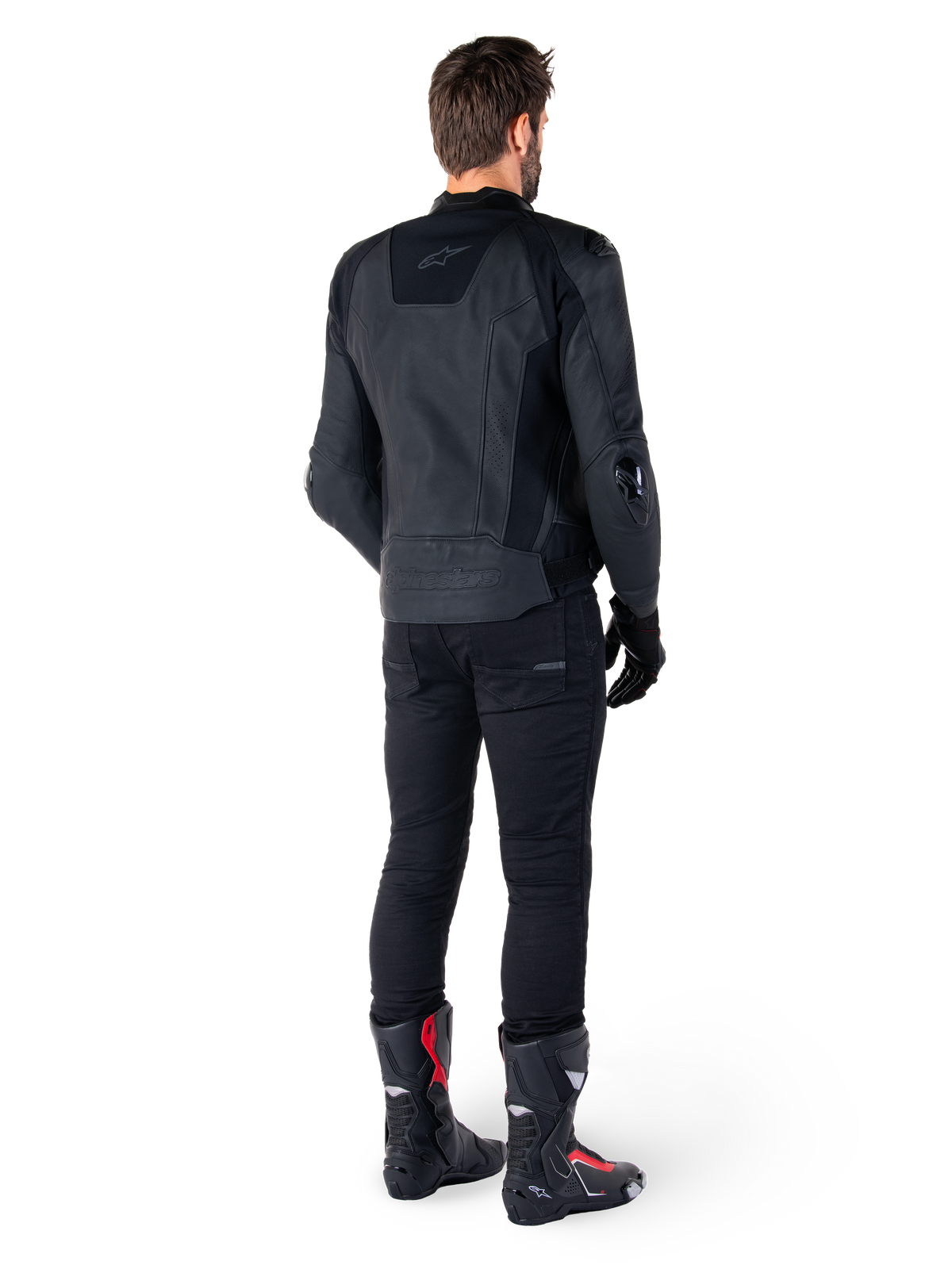 Alpinestars Missile V3 Lederjacke in Schwarz, Rückansicht an einem Fahrer, getragen mit schwarzer Hose und schwarz-roten Rennstiefeln, elegante Lederkonstruktion mit dezentem Branding und Performance-Passform für den Rennsport