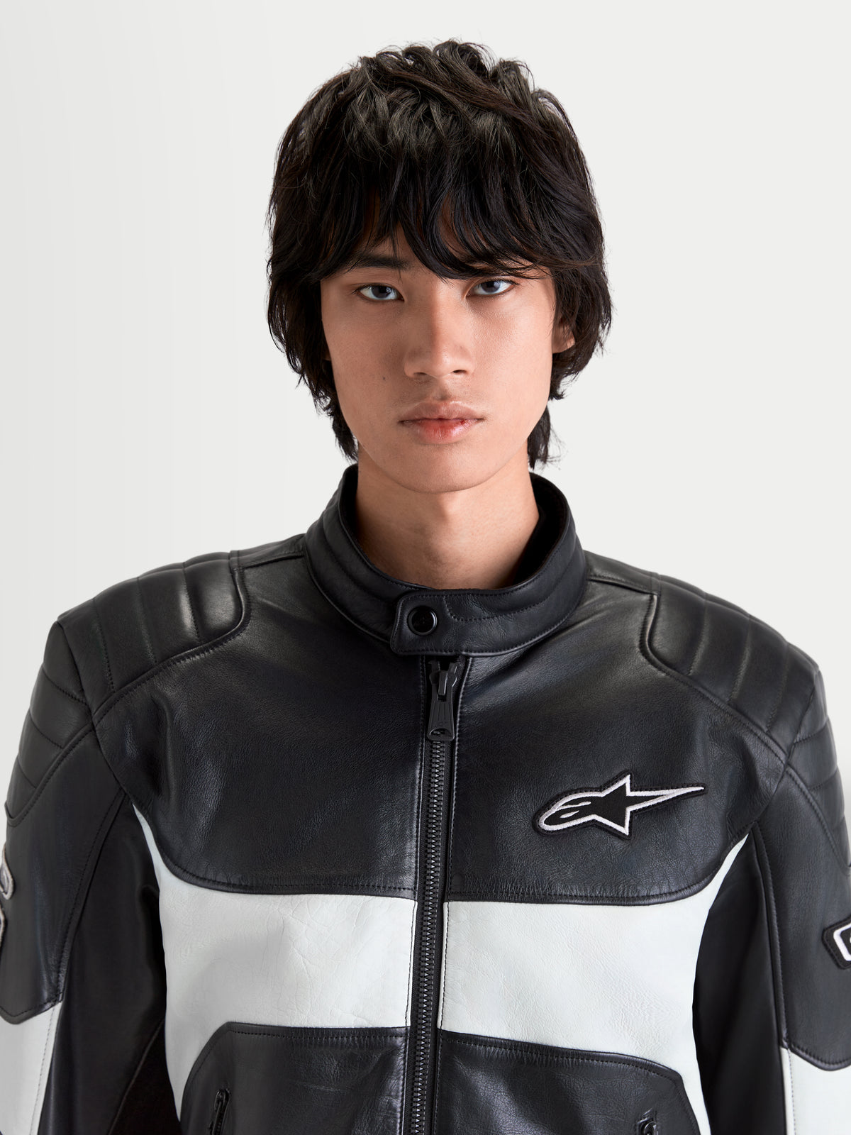 Alpinestars Revern Lederjacke, urbane Motorrad-Lederjacke für Herren in Schwarz und Metallgrau, Nahaufnahme der Vorderseite an einem Model mit Vollnarbenleder, Biker-Kragen und weißem Alpinestars-Logobranding