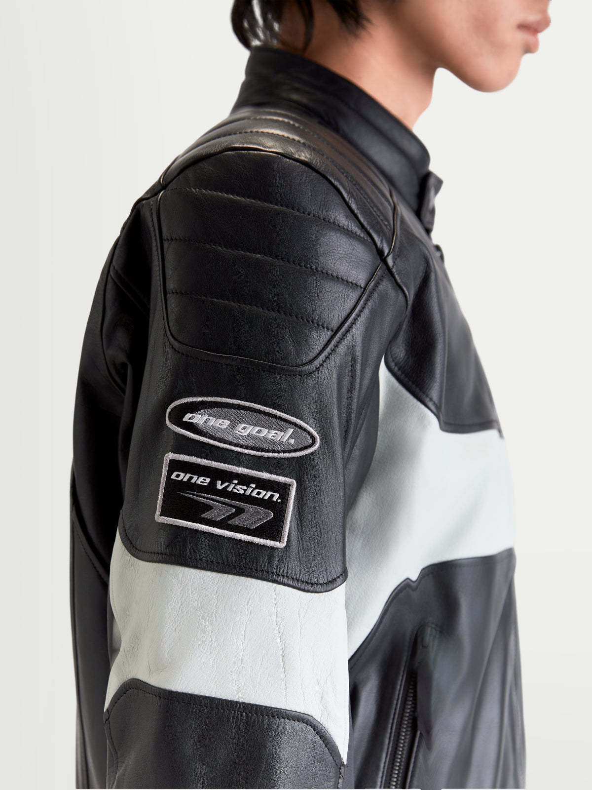 Alpinestars Revern Lederjacke, urbane Herren-Motorradlederjacke in Schwarz und Metallgrau, Seitenprofil-Nahaufnahme mit heritage-inspirierten Branding-Aufnähern am Ärmel und Konstruktion aus gewaschenem Rindsleder an einem Model