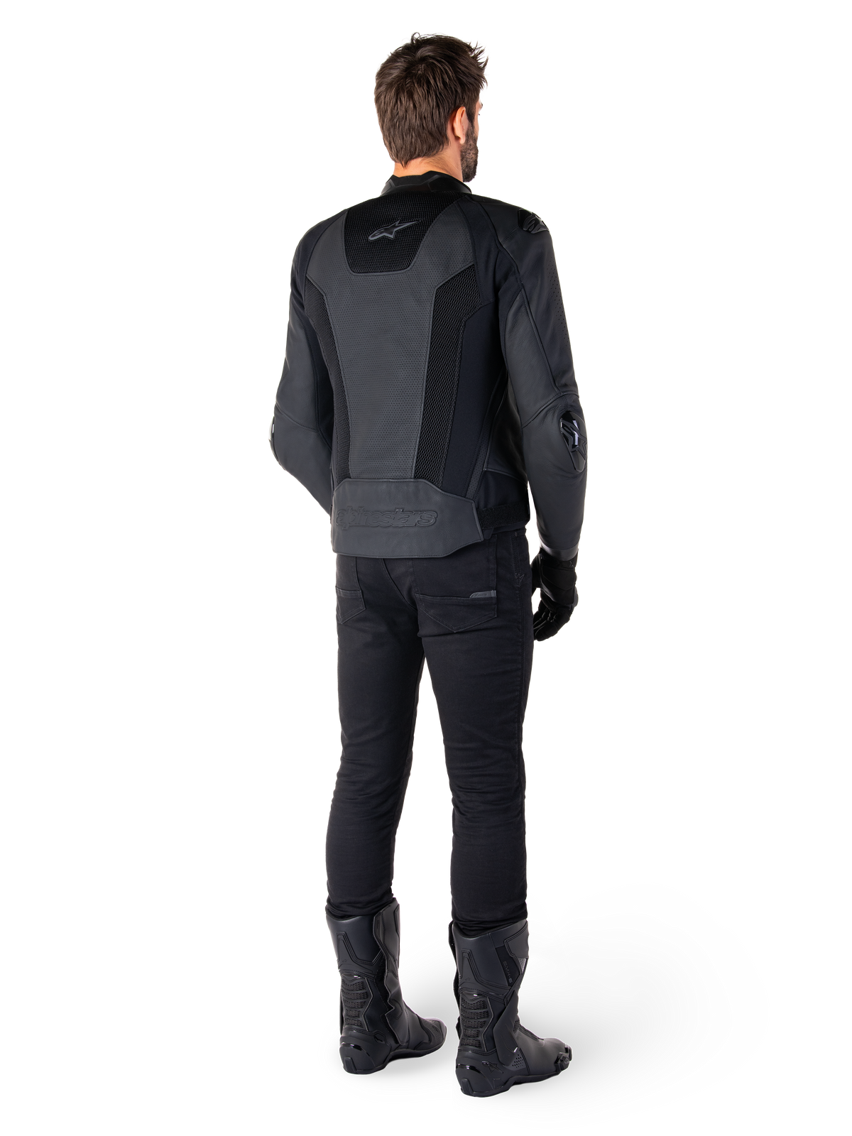Rückansicht eines Mannes in der Alpinestars Missile V3 Airflow Lederjacke in Schwarz, mit großflächigen perforierten Einsätzen zur Belüftung, kombiniert mit schwarzer Motorradhose und Stiefeln, eine stromlinienförmige Rennsport-Ästhetik präsentierend.