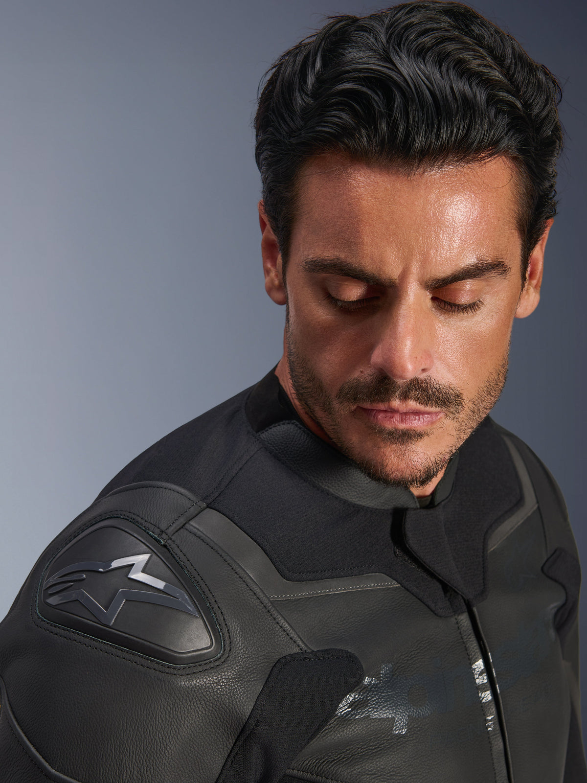 Alpinestars GP Force V2 Lederjacke, Schwarz, Nahaufnahme eines männlichen Models beim Tragen der Jacke, Fokus auf die Schulter mit dem GP Lite Evo DFS-Protektor und Alpinestars-Logo, hochwertige mehrpanelige Lederkonstruktion