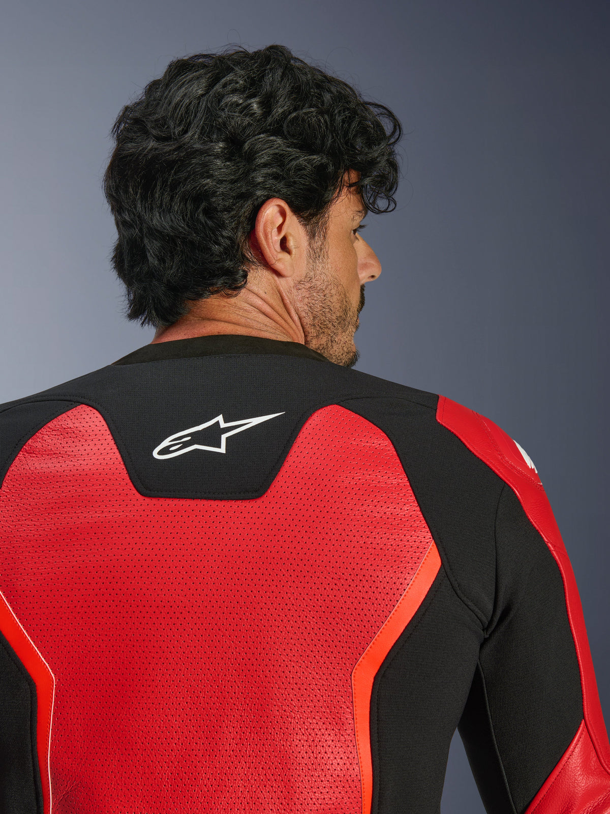 Alpinestars GP Force V2 Air Leather Jacket, Red and Black, close-up back view featuring extensive perforated leather for airflow, black stretch panel with white Astars logo, sport-fit motorcycle riding jacket