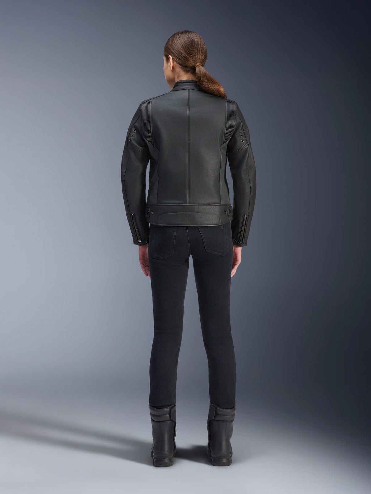 Alpinestars Stella Dyno Lederjacke, Damen-Motorradjacke, Schwarz, Rückansicht zur Hervorhebung der maßgeschneiderten Rindslederkonstruktion, minimalistisches Heritage-Design, getragen mit schwarzer Motorradhose und Stiefeln für einen urbanen Motorrad-Look