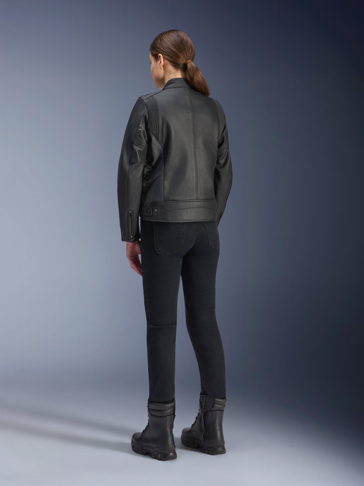 Alpinestars Stella Dyno Lederjacke, Damen-Motorradjacke, Schwarz, Rückansicht mit hochwertiger Lederkonstruktion und maßgeschneiderter Passform, kombiniert mit schwarzer Motorradhose und schwarzen Stiefeln, urbaner Fahrstil.