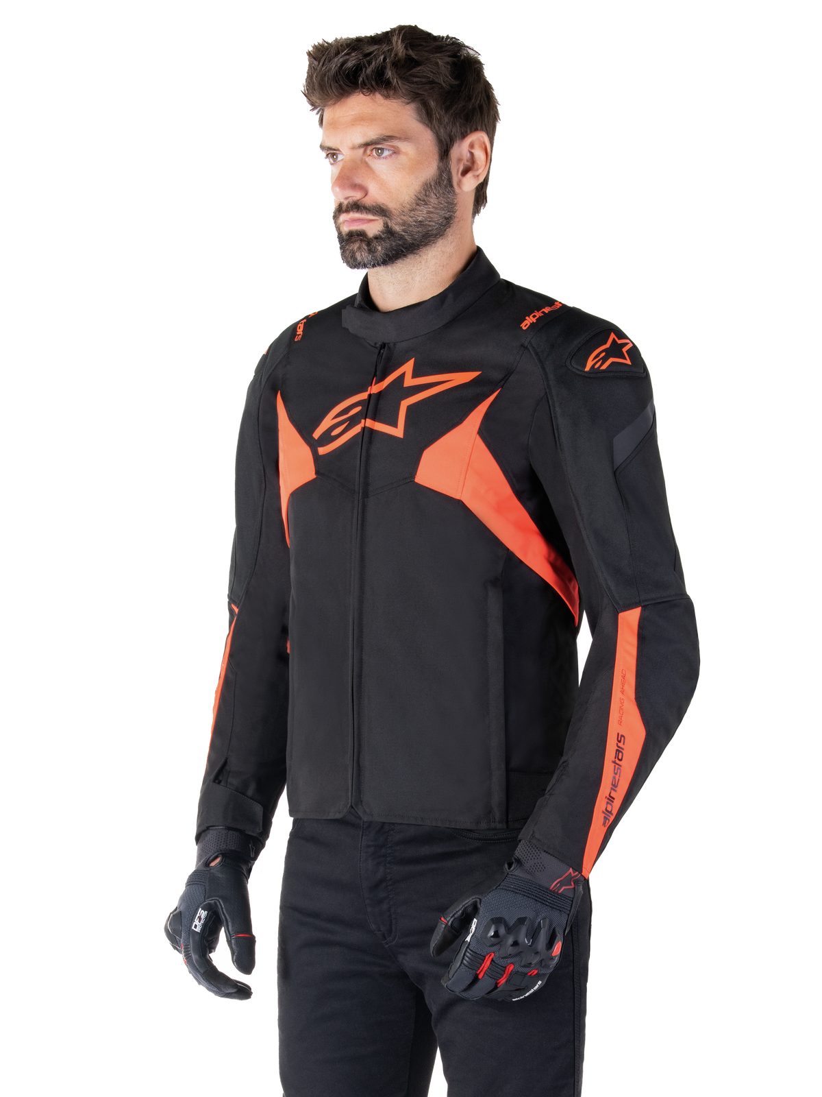 Alpinestars T-Jaws V4 Wasserdichte Jacke, Schwarz und Rot Fluo, sportliche Motorradjacke getragen von einem männlichen Model, mit markanten orangefarbenen Stern-Logos auf der Brust und den Schultern, kombiniert mit schwarzen Handschuhen und Hosen