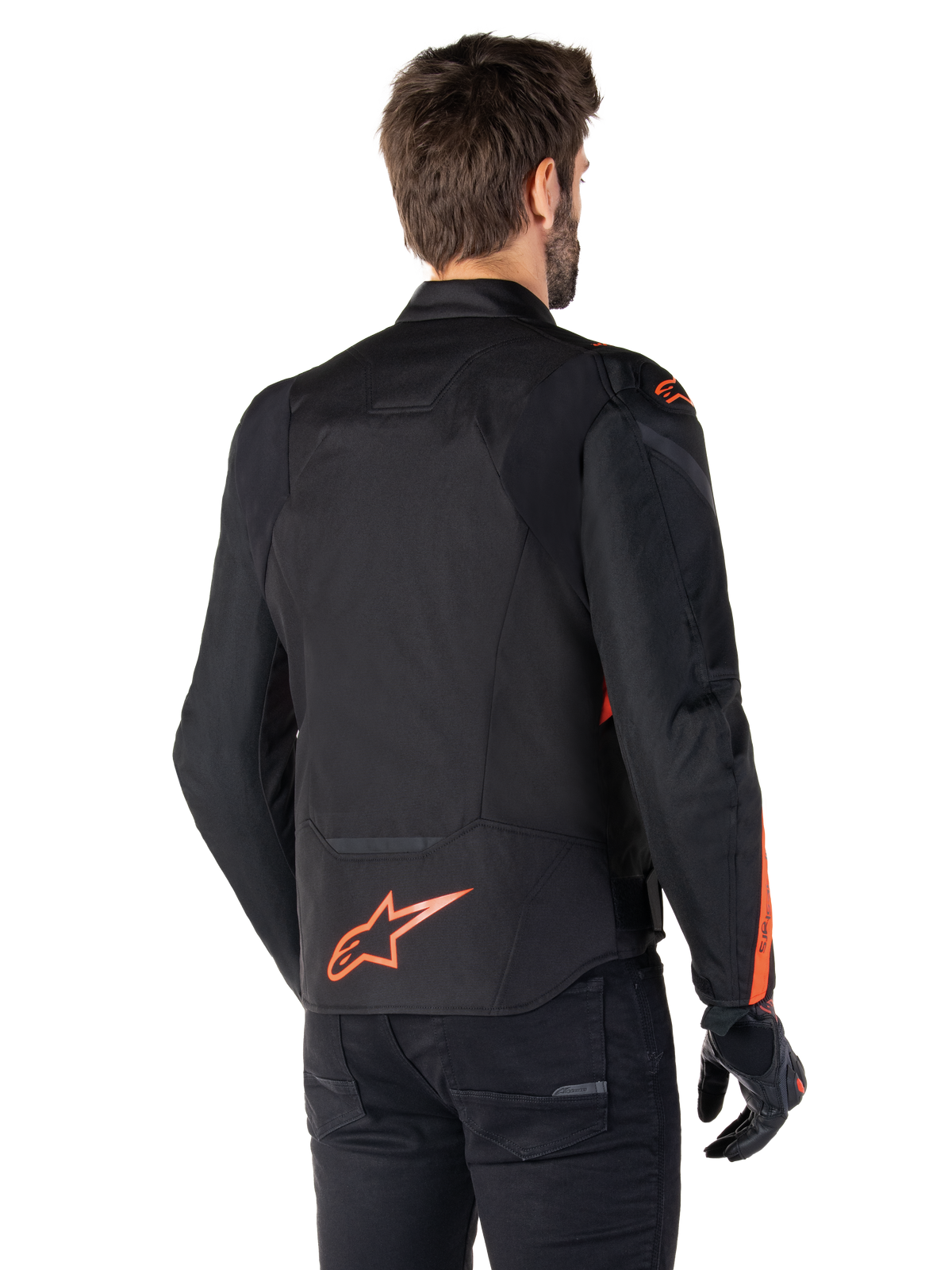 Männliches Modell in der Alpinestars T-Jaws V4 Wasserdichten Jacke in der Rückansicht, Schwarz mit Red Fluo Akzenten, mit einem Red Fluo Logo am unteren Rücken und Akzenten an den Schultern und Ärmeln, sportliche Motorradbekleidung.