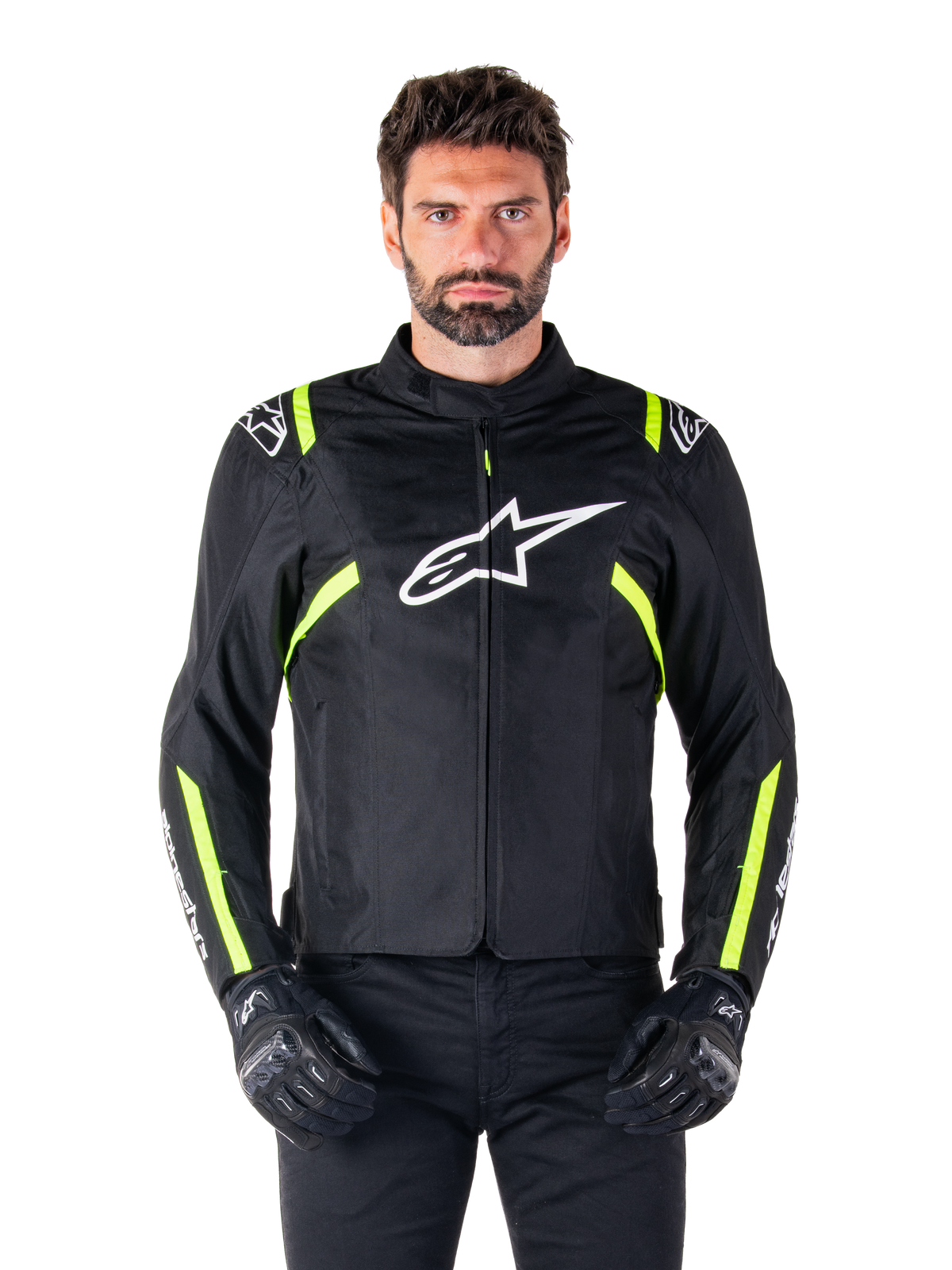 Alpinestars T-SPS V2 Waterproof Jacke, Motorradjacke, Schwarz mit weißen und neongelben Akzenten, getragen von einem Model mit schwarzen Handschuhen, mit weißem Stern-Logo auf der Brust und neongelben Streifen an Ärmeln und Schultern, sportliche Textilausrüstung für jedes Wetter