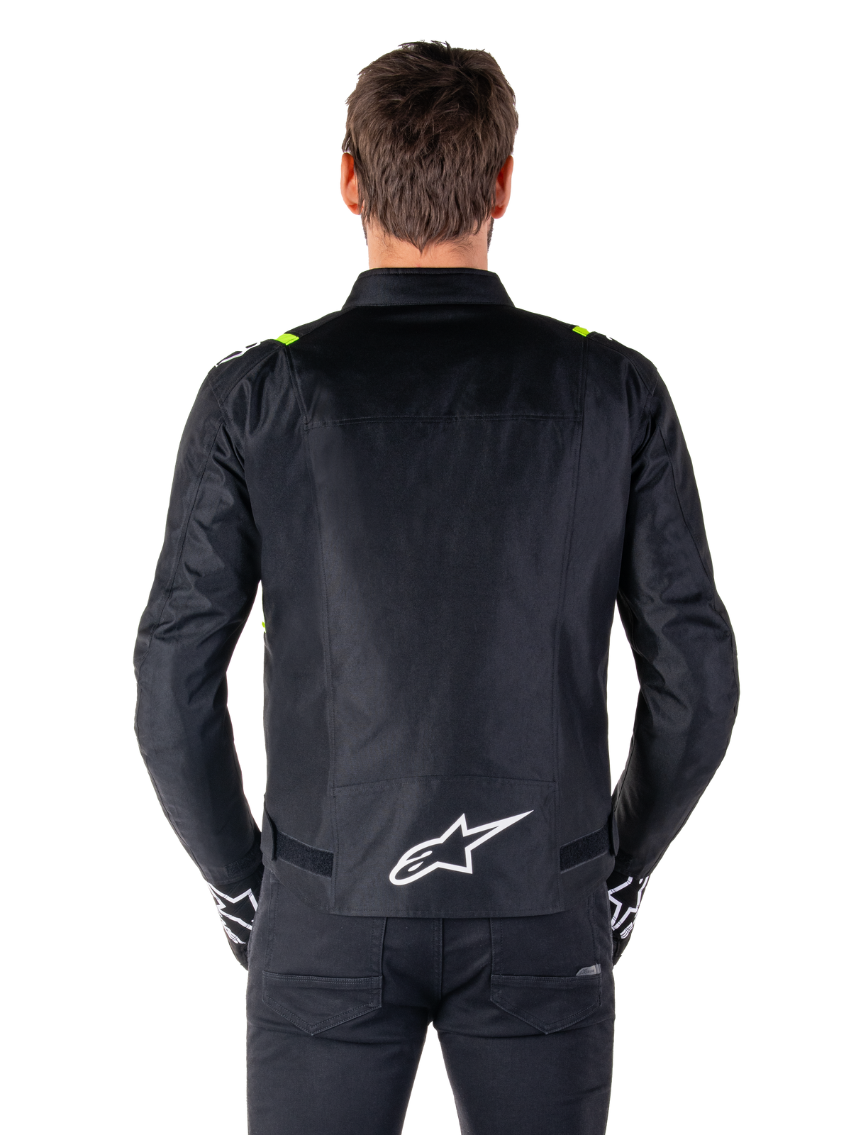 Alpinestars T-SPS V2 Wasserdichte Jacke, Rückansicht, Schwarz mit Yellow Fluo Akzenten an den Schultern und weißem Stern-Logo auf dem unteren Rücken, Textil-Motorradjacke mit sportlicher Silhouette, von einem männlichen Model getragen