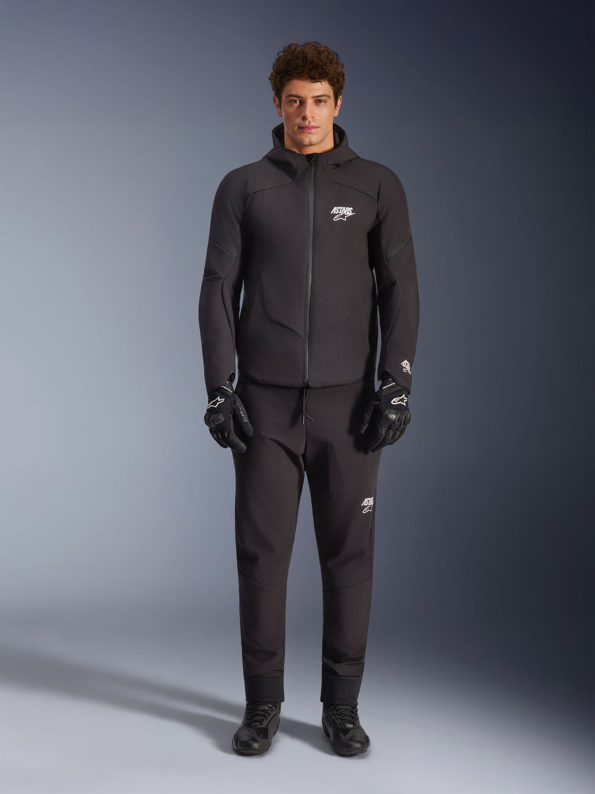 Alpinestars Aeroshell Waterproof Jacket, black hooded softshell motorcycle jacket for road riding, worn by male model.
