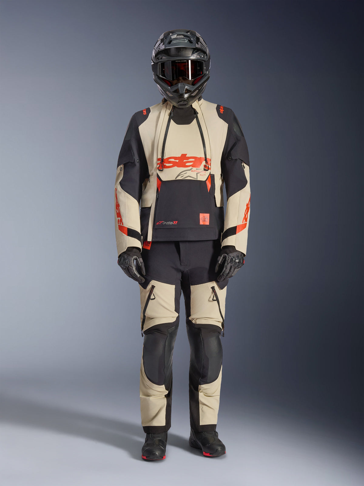 Alpinestars Halo Pro Drystar® XF Laminierte Jacke, Adventure-Motorradjacke, Mastic Black, Beige und Schwarz mit orangefarbenen Akzenten, getragen mit passender Hose, Helm und Handschuhen, technisches Design mit wasserdichten Reißverschlüssen und modularen Paneelen für Offroad- und Straßeneinsatz