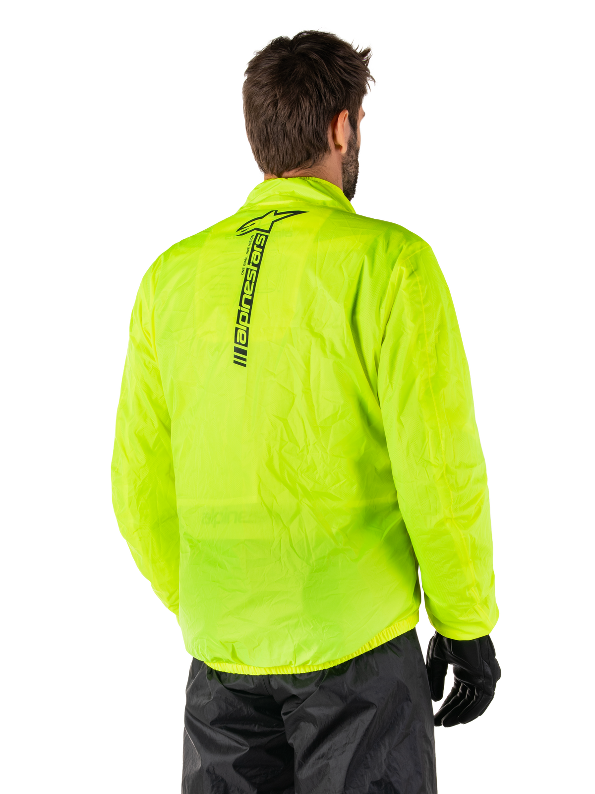 Alpinestars Hurricane Rain V2 Jacke, Gelb Fluo, Rückansicht an einem männlichen Model, vertikale schwarze Alpinestars-Wortmarke auf dem Rücken, elastischer Bund und Ärmelbündchen, wasserdichtes und packbares Design