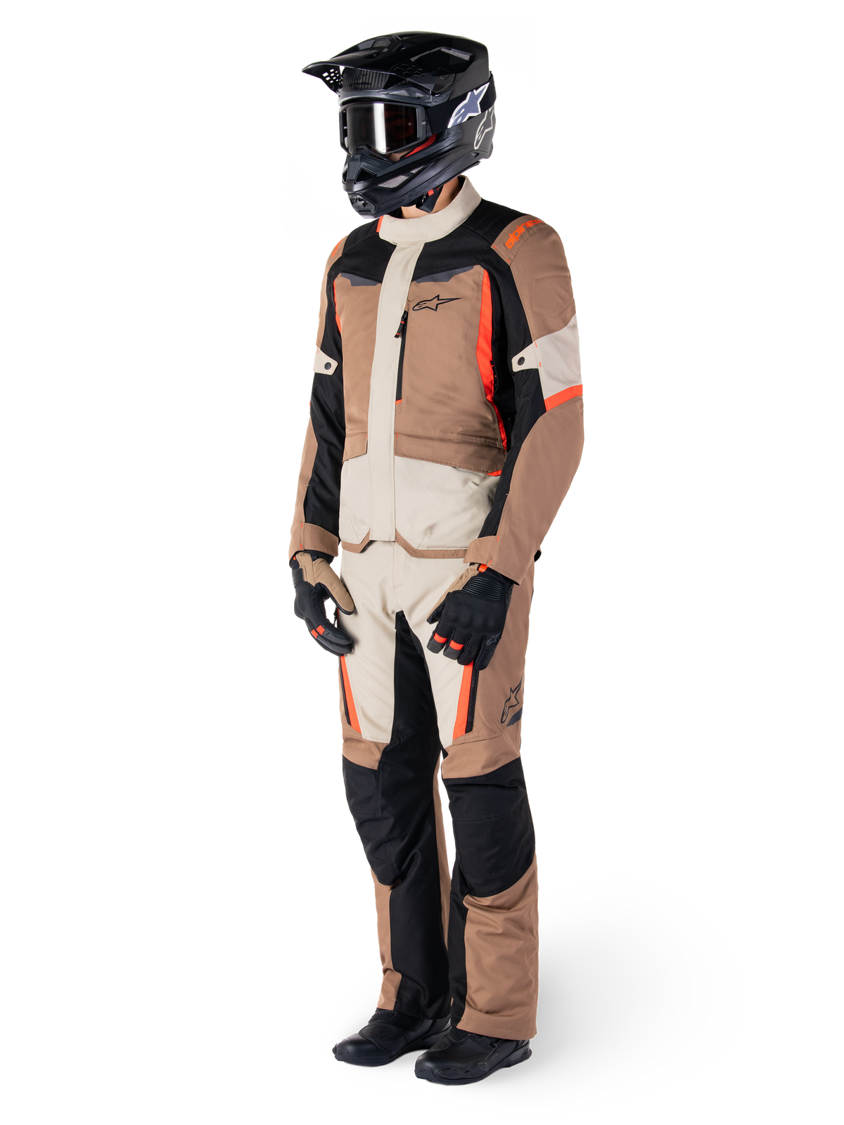 Alpinestars ST-1 Wasserdichte Jacke, Dark Khaki Sand Black Red Fluo, getragen von einem Fahrer in kompletter Adventure-Touring-Ausrüstung mit passender Hose, schwarzem Helm, Schutzbrille, Handschuhen und Stiefeln, technische Allwetter-Motorradausrüstung.