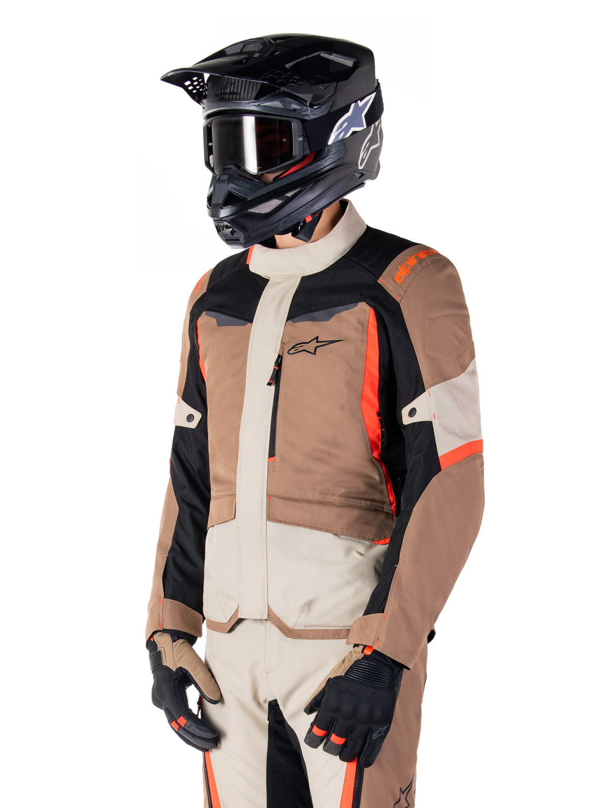 Alpinestars ST-1 Wasserdichte Jacke, Adventure-Touring-Jacke, Dark Khaki Sand Black und Red Fluo, getragen von einem Fahrer mit einem schwarzen Motocross-Helm und einer Brille, mit einem Multi-Panel-Design mit Cargo-Taschen und Alpinestars-Branding auf der Brust
