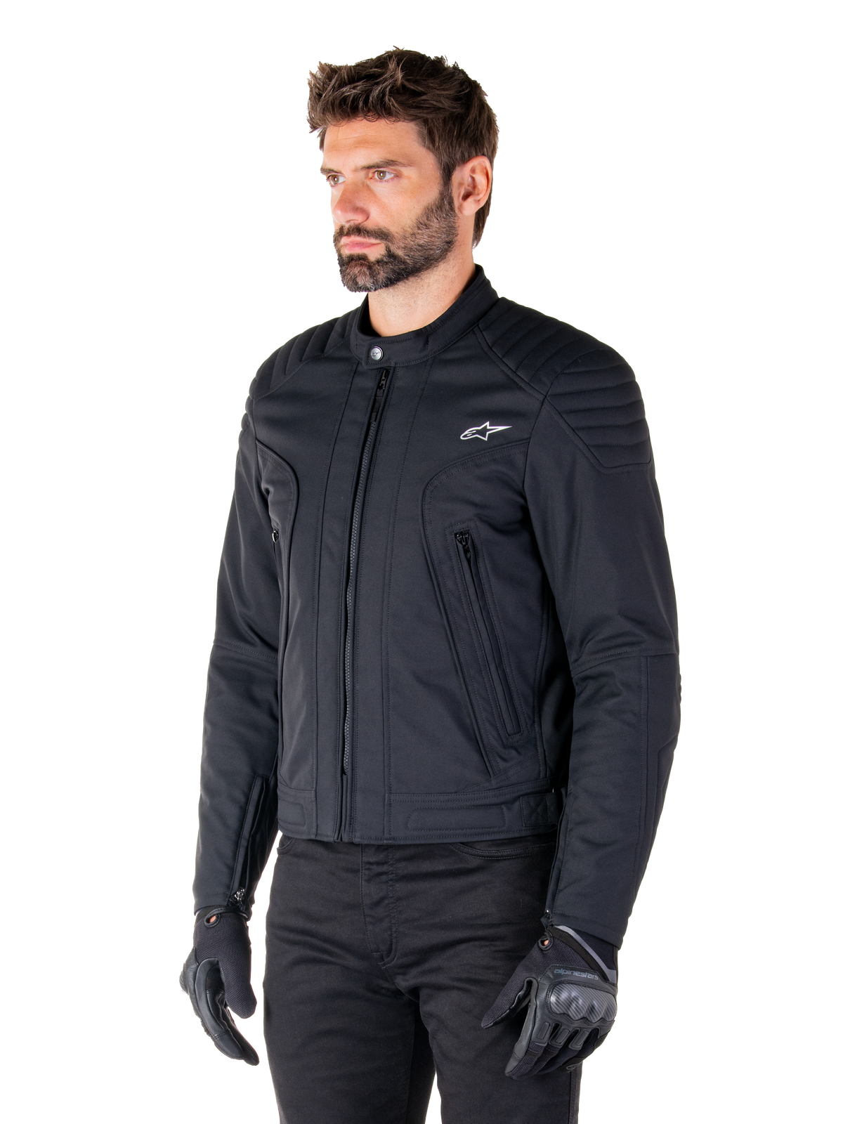 Alpinestars Clayton WR Jacke, Schwarz, urbane Textil-Motorradjacke mit gesteppten Schulter- und Unterarmdetails, schmale Passform, mattes Finish, getragen von einem Fahrer mit schwarzen Handschuhen.