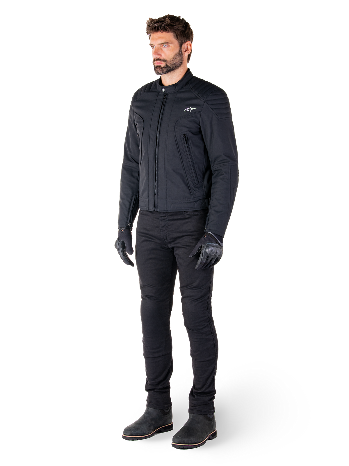 Männlicher Fahrer in der Alpinestars Clayton WR Jacke, schwarze Urban-Motorradjacke, Slim-Fit-Design mit gesteppten Schulterakzenten und mattem Finish, kombiniert mit schwarzer technischer Motorradhose und Handschuhen.