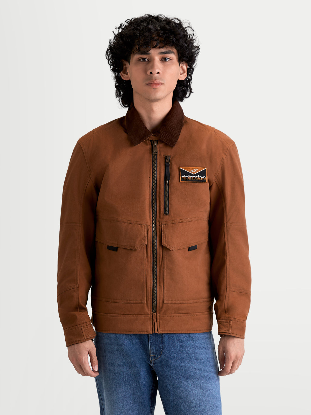 Alpinestars Mustang Wp Jacke, urbane Herren-Motorradjacke in Rostbraun und Dunkelbraun, Frontansicht an einem Model mit Arbeitskleidungs-Stil und Cordkragen