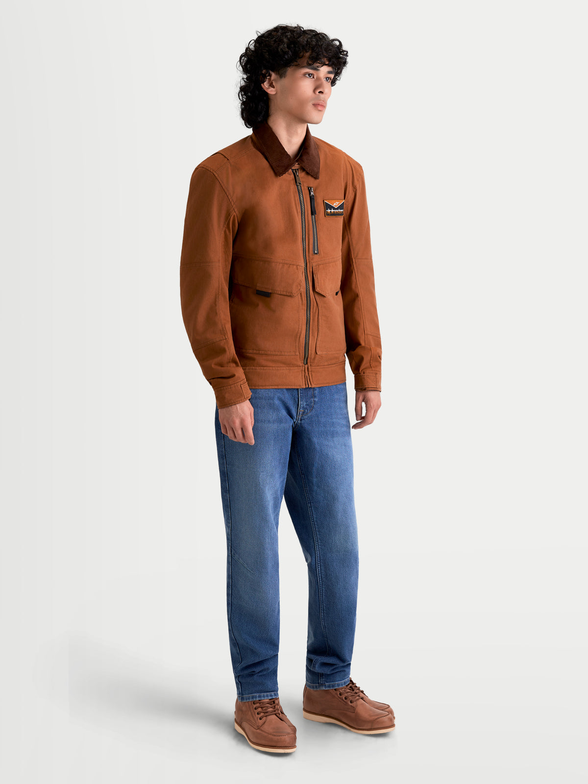 Alpinestars Mustang WP Jacke, urbane Motorradjacke für Herren in Rostbraun und Dunkelbraun, Seitenprofil-Ansicht an einem Model in textiler Arbeitskleidung und blauen Jeans