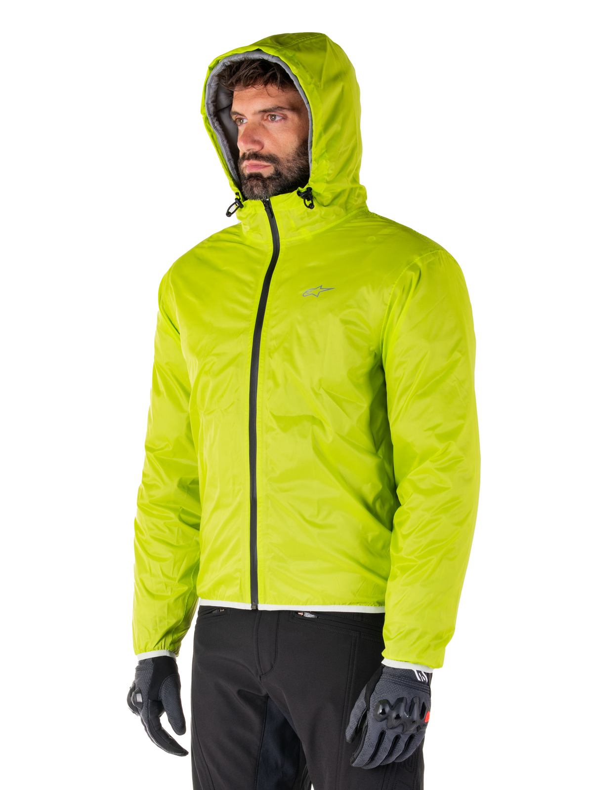 Alpinestars Mohobbs Wasserdichte Jacke, verstaubares Regenfutter in Lime Punch, leuchtend neongrüne Kapuzenjacke, kombiniert mit schwarzer Hose und grauen Handschuhen, von Urban Streetwear inspirierte Motorradbekleidung