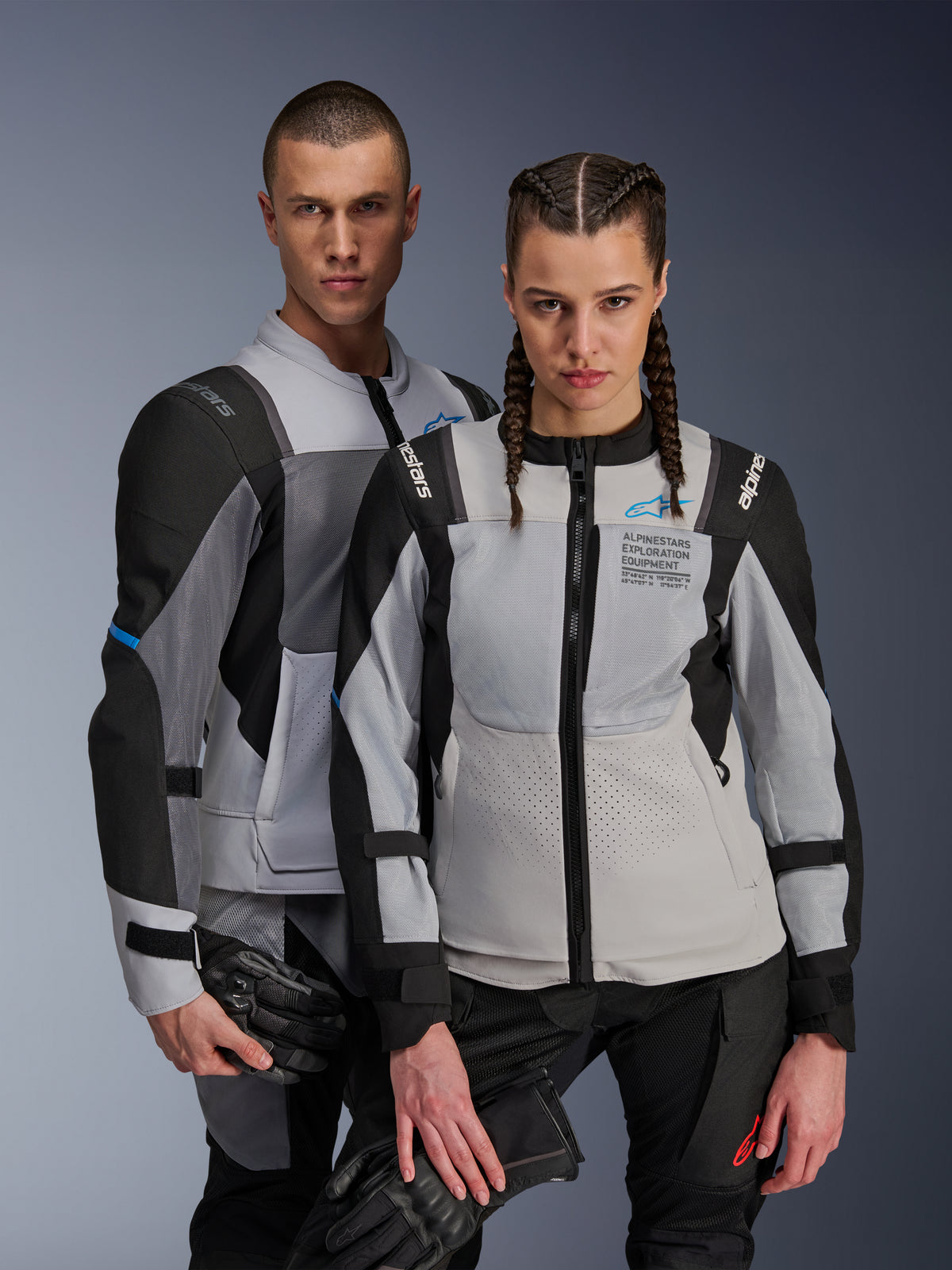 Alpinestars ST-2 Air and Stella ST-2 Air Jackets, Ice Gray and Black, textile motorcycle jackets with mesh panels and laser perforations, featuring 'Alpinestars Exploration Equipment' branding, worn by male and female models holding riding gloves.