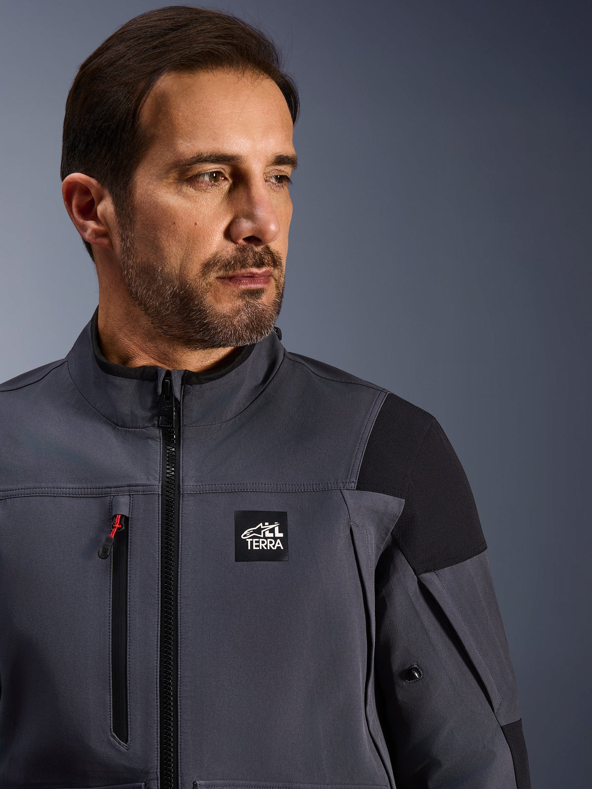 Alpinestars Maxdura Drystar®XF Laminierte Gepanzerte Schale, technische Adventure-Jacke, Dunkelgrau und Schwarz, mit 'ALL TERRA'-Branding auf der Brust, wasserdichtem Brustreißverschluss mit rotem Akzent und High-Performance-Textildesign für den Adventure-Motorradsport