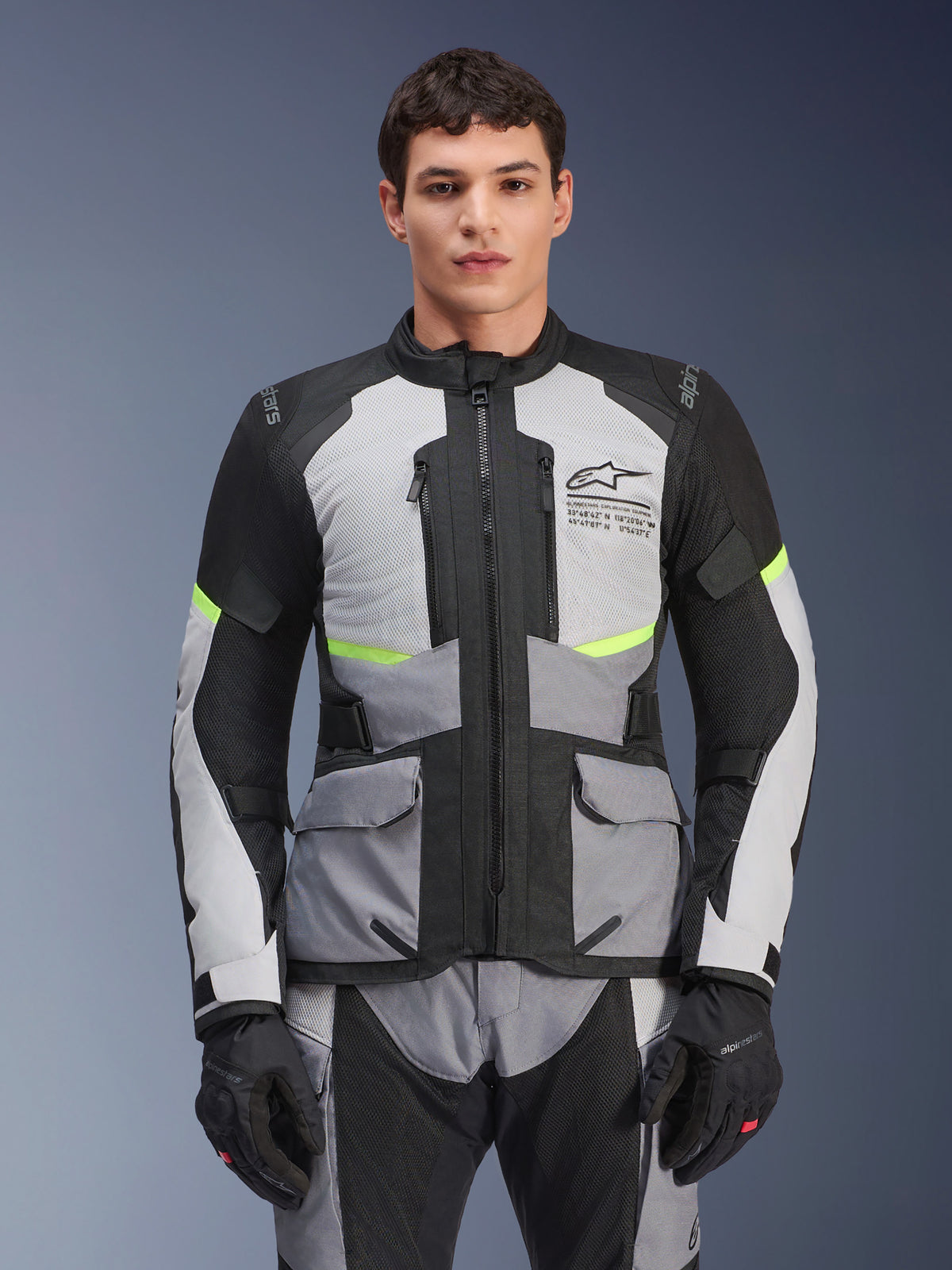 Alpinestars Andes Air Drystar Jacket, Adventure Touring Motorcycle Jacket, Ice Gray and Dark Gray with Black panels and Neon Yellow accents, worn with matching pants and gloves, featuring mesh ventilation panels and cargo pockets
