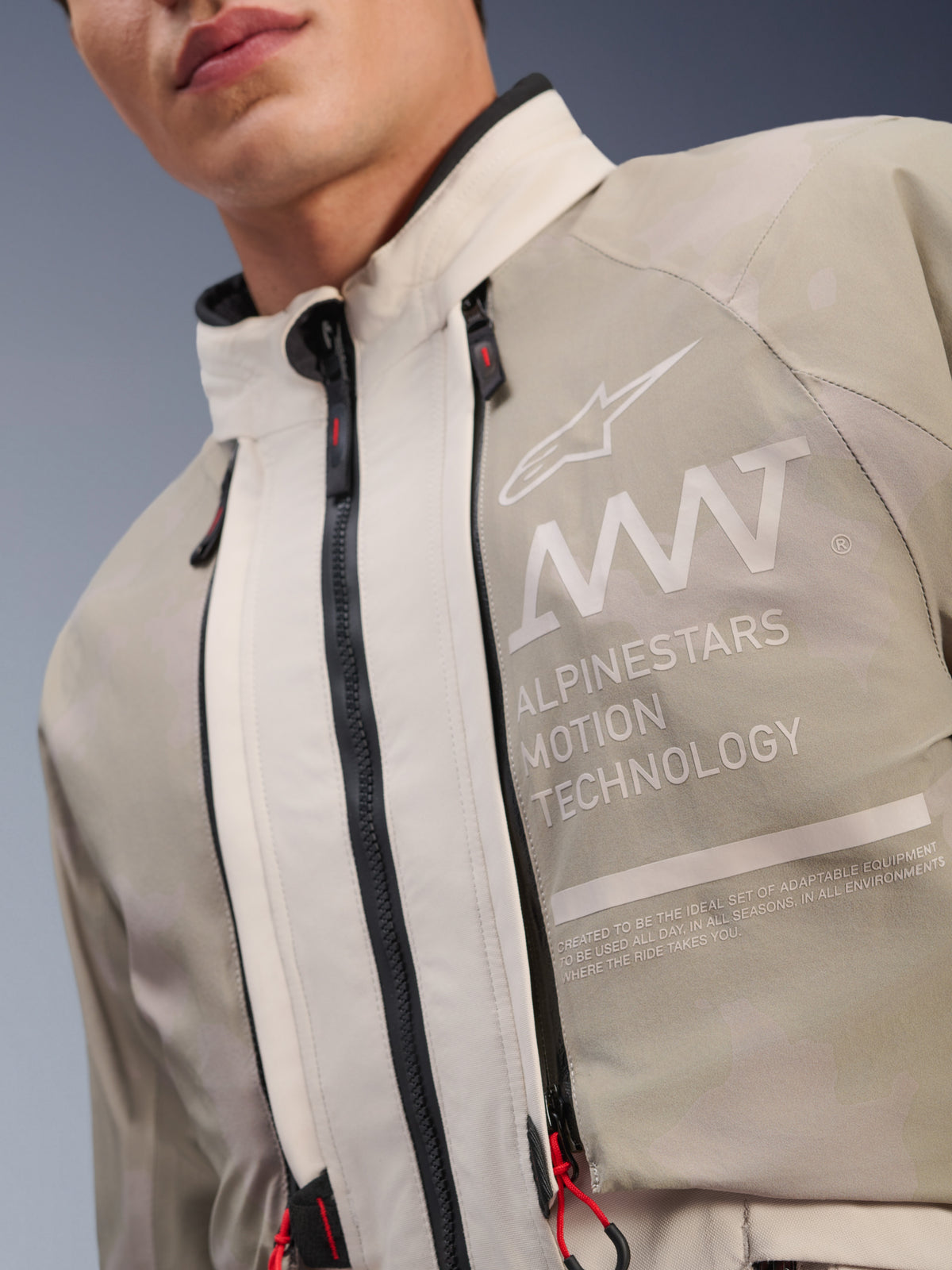 Alpinestars AMT-10LAB Drystar® XF Jacket, White Sand Aluminum Camo, close-up of chest featuring AMT Alpinestars Motion Technology branding, waterproof zippers with red pull tabs, and textured adventure-ready textile fabric.