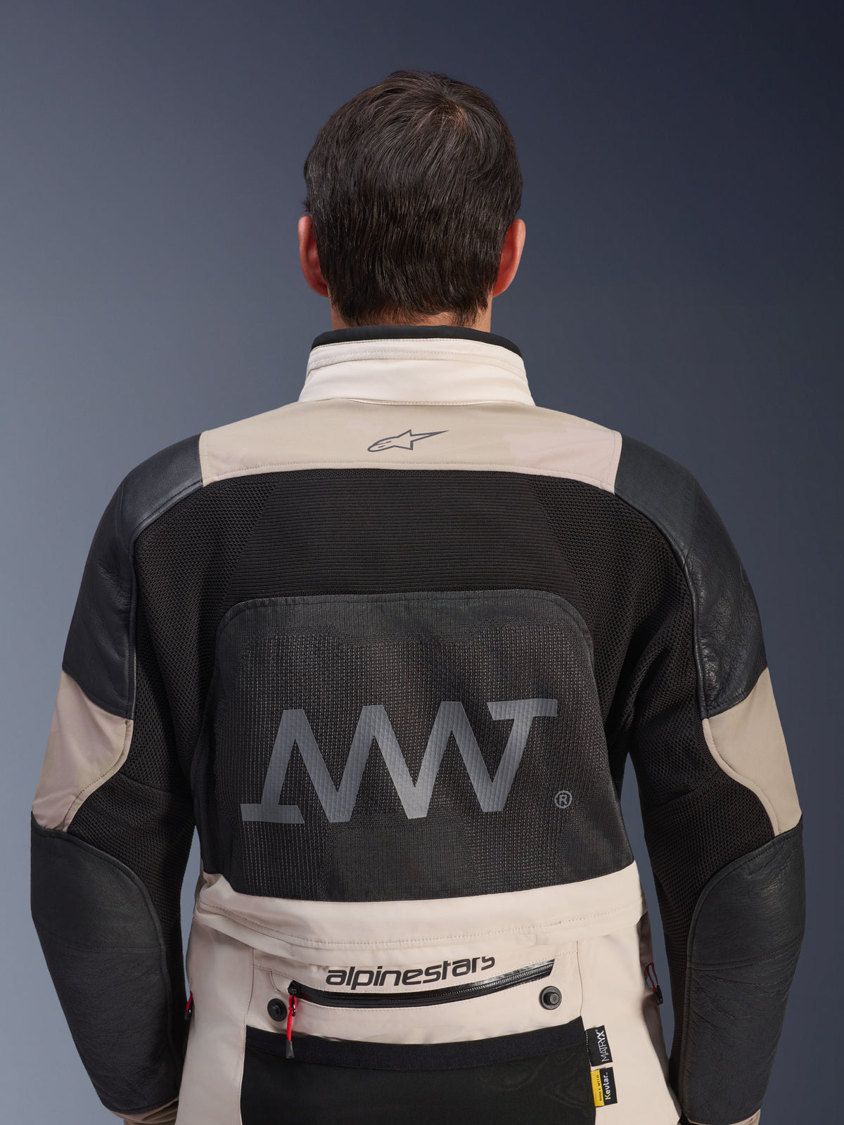 Rear view of Alpinestars AMT-10LAB Drystar® XF Jacket in White Sand and Black, featuring a large AMT logo on the mesh back panel, Alpinestars branding on the lower back, and technical textile construction for adventure motorcycling