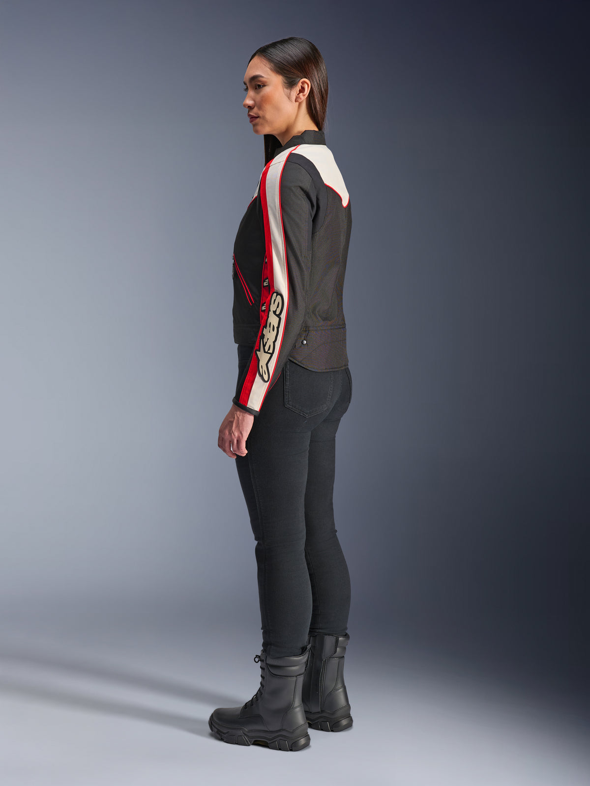 Alpinestars Stella T-Dyno WR Jacke, Damen-Textilmotorradjacke, Schwarz, Ecru und Hellrot, Vintage-inspiriertes Design mit Astars-Branding am Ärmel, getragen mit schmaler schwarzer Hose und schwarzen Stiefeln, kurzer Biker-Schnitt für urbane Straßenfahrten