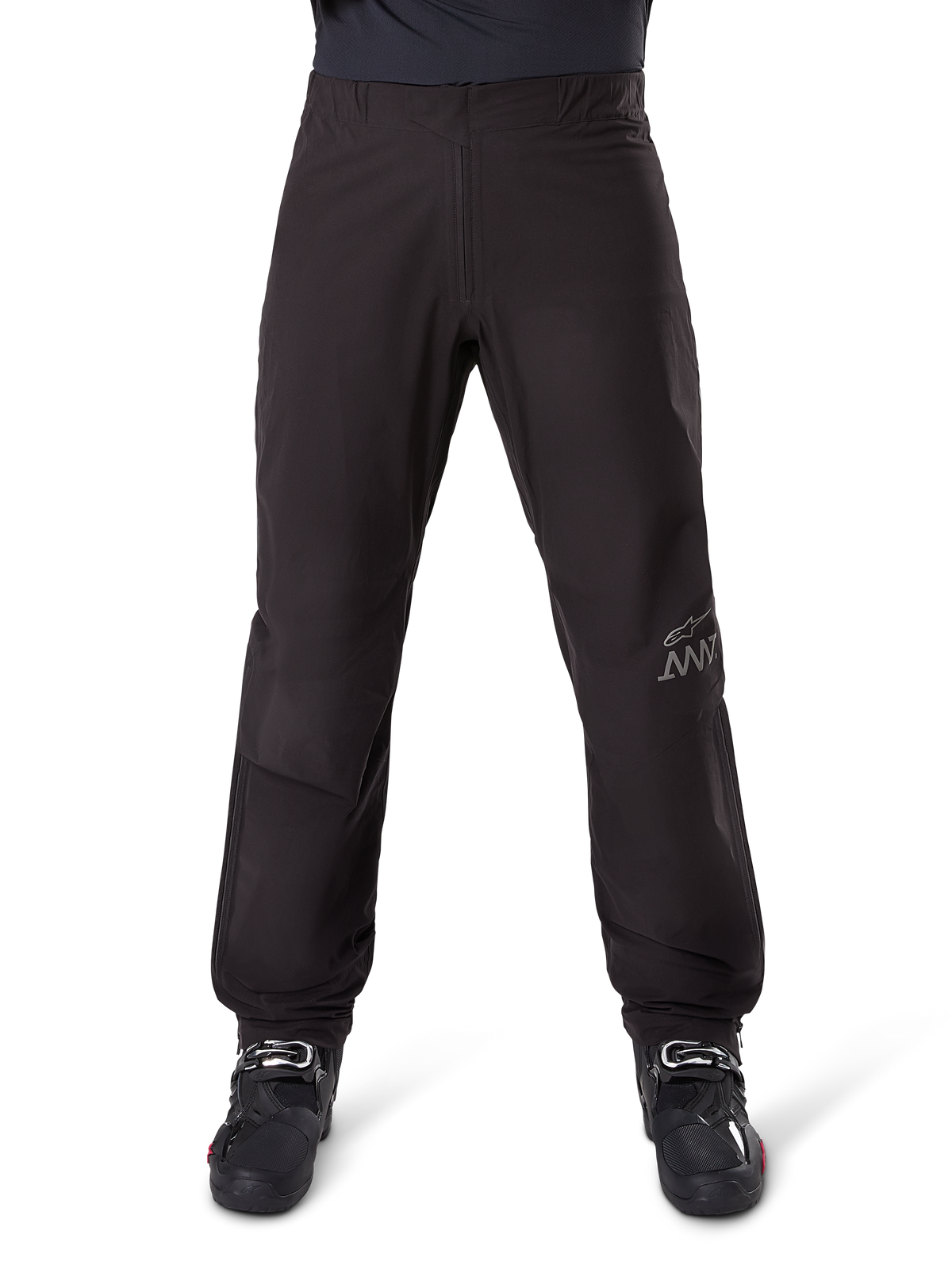 Alpinestars AMT-8 Stretch Drystar® XF Pant Liner, Schwarz, Vorderansicht getragen mit schwarzen Motorradstiefeln, mit grauem Stern-Logo und AMT-Branding am Bein, vielseitige wasser- und winddichte Motorradbekleidung