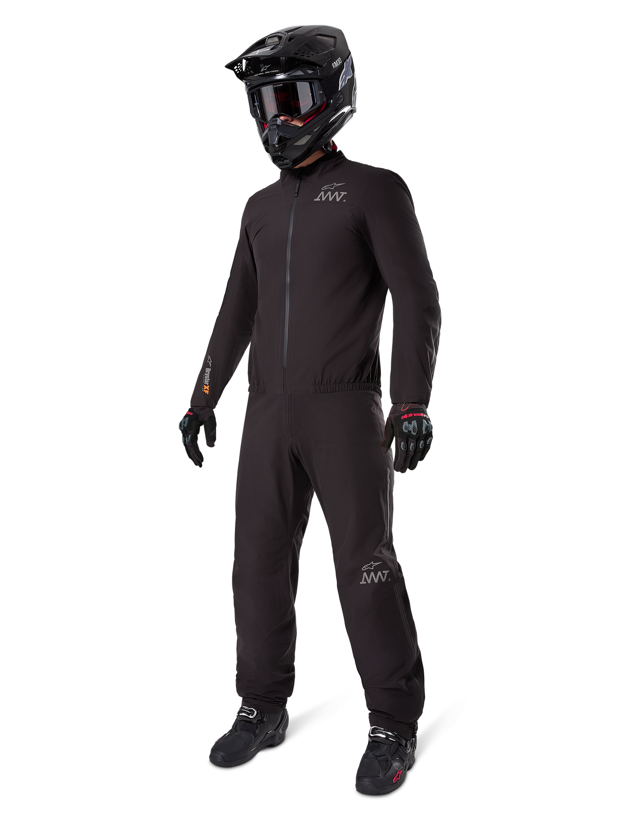 Alpinestars AMT-8 Stretch Drystar XF Liner, komplett schwarzer Adventure-Tourenanzug, wasser- und winddichte Jacke und Hose, kombiniert mit einem schwarzen Adventure-Helm, Brille, Handschuhen und Motorradstiefeln, mit AMT-Logos und Drystar XF-Branding an Ärmeln und Beinen.